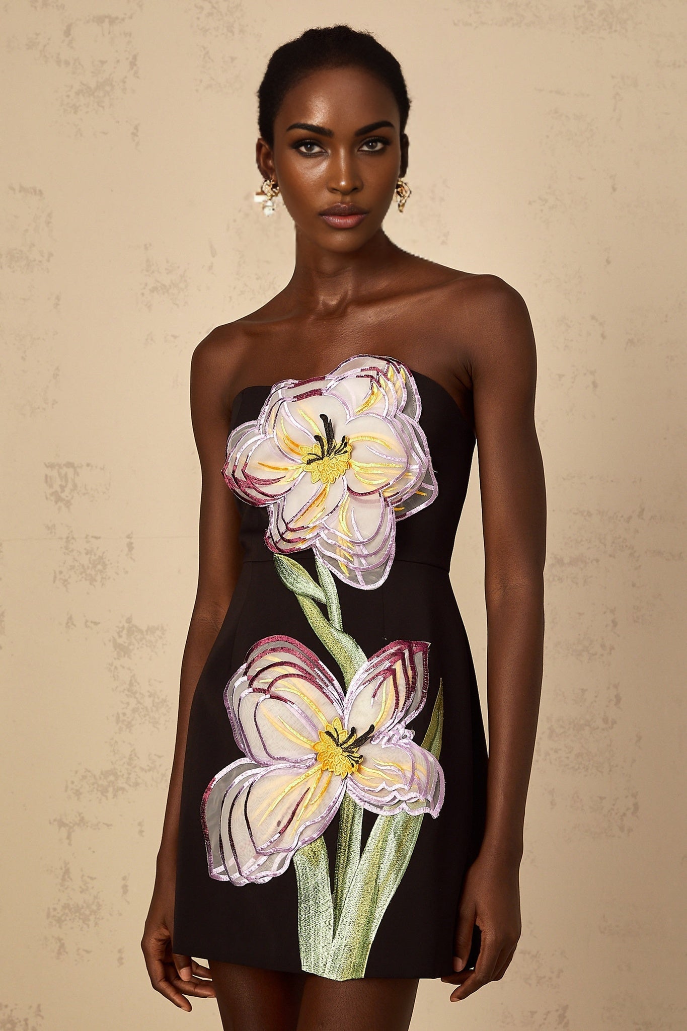 A black off shoulder mini dress with sequin and floral embroidery details worn by a woman named Irene