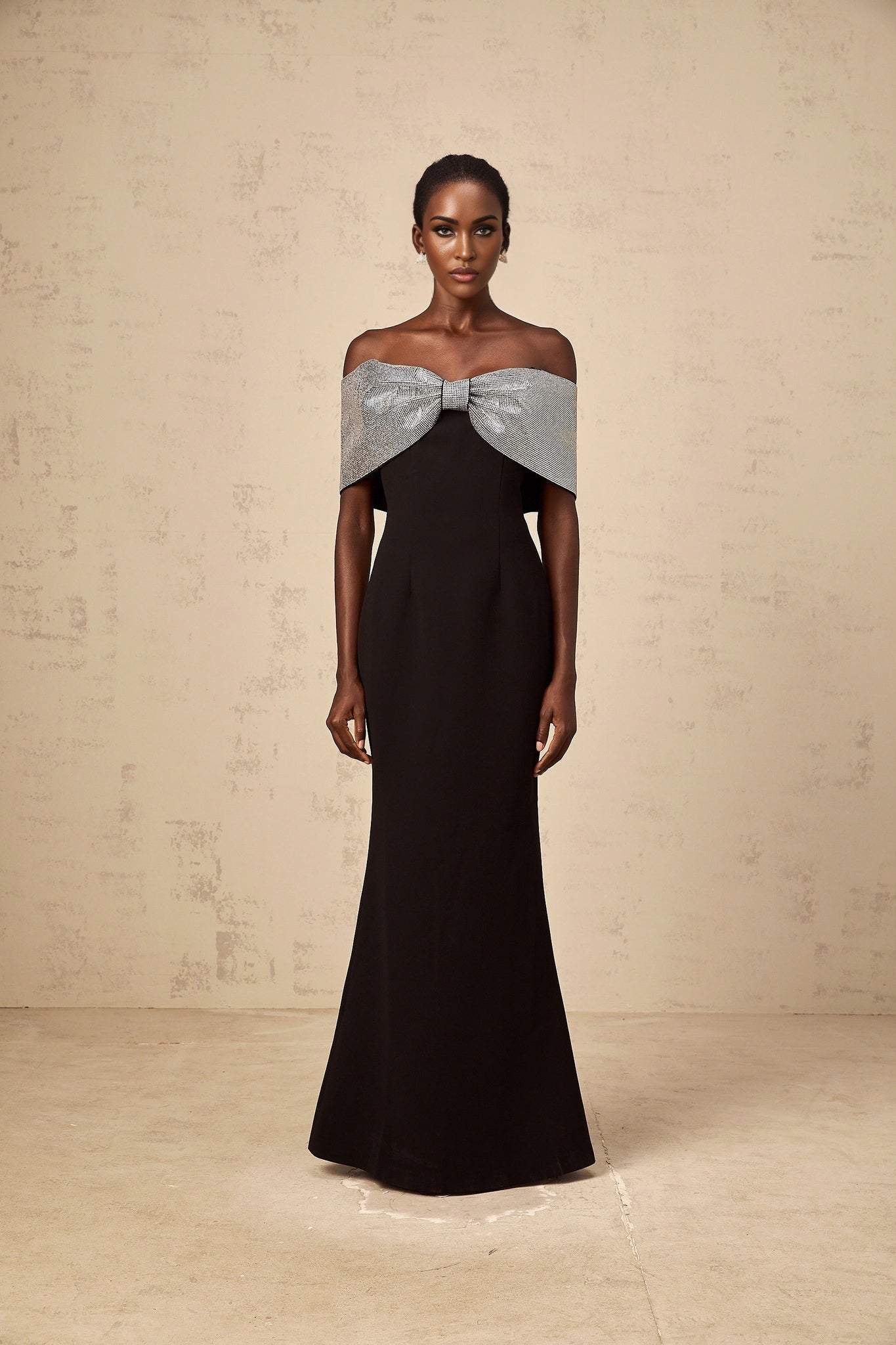 A black offshoulder maxi dress by Chloé featuring a rhinestone bow accent