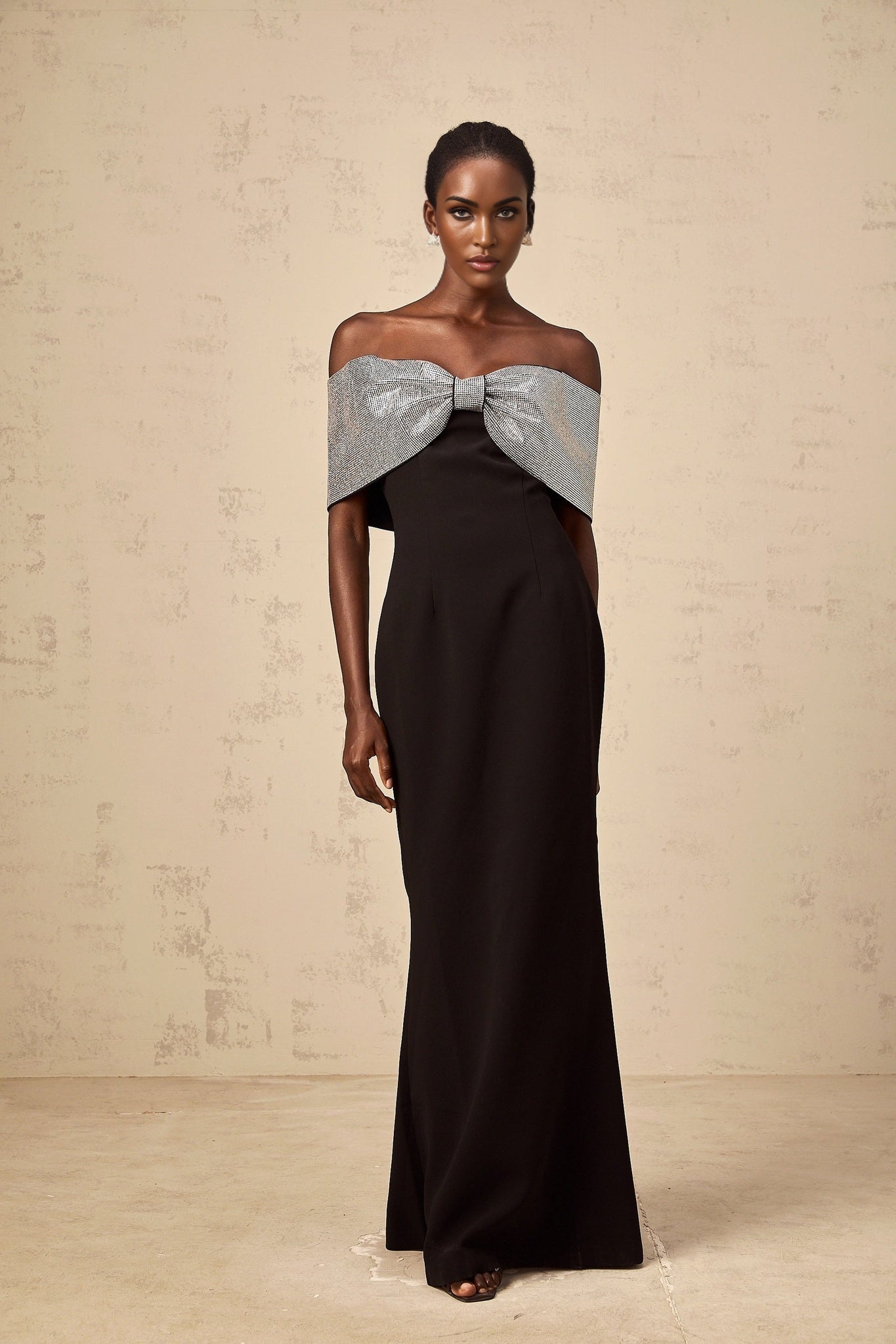 A black offshoulder maxi dress with a rhinestone bow detail designed by Chloé