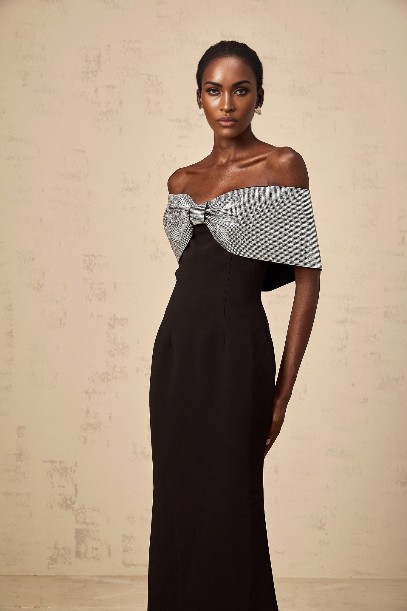 A black offshoulder maxi dress with a rhinestone bow detail designed by Chloé