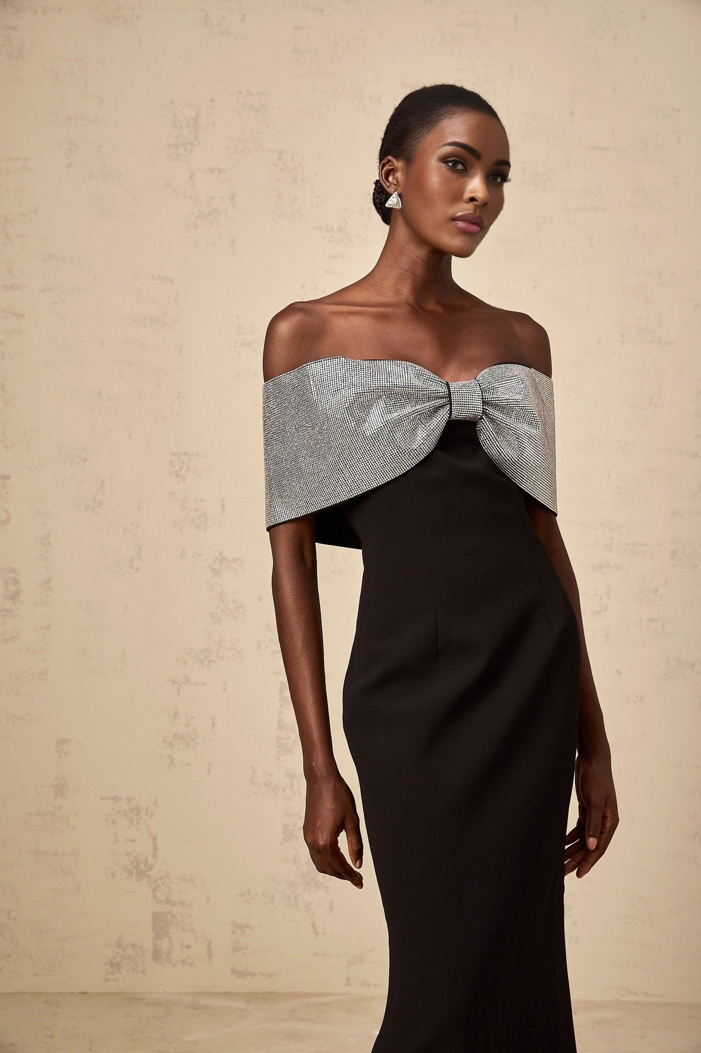 A black offshoulder maxi dress with a rhinestone bow detail made by Chloé