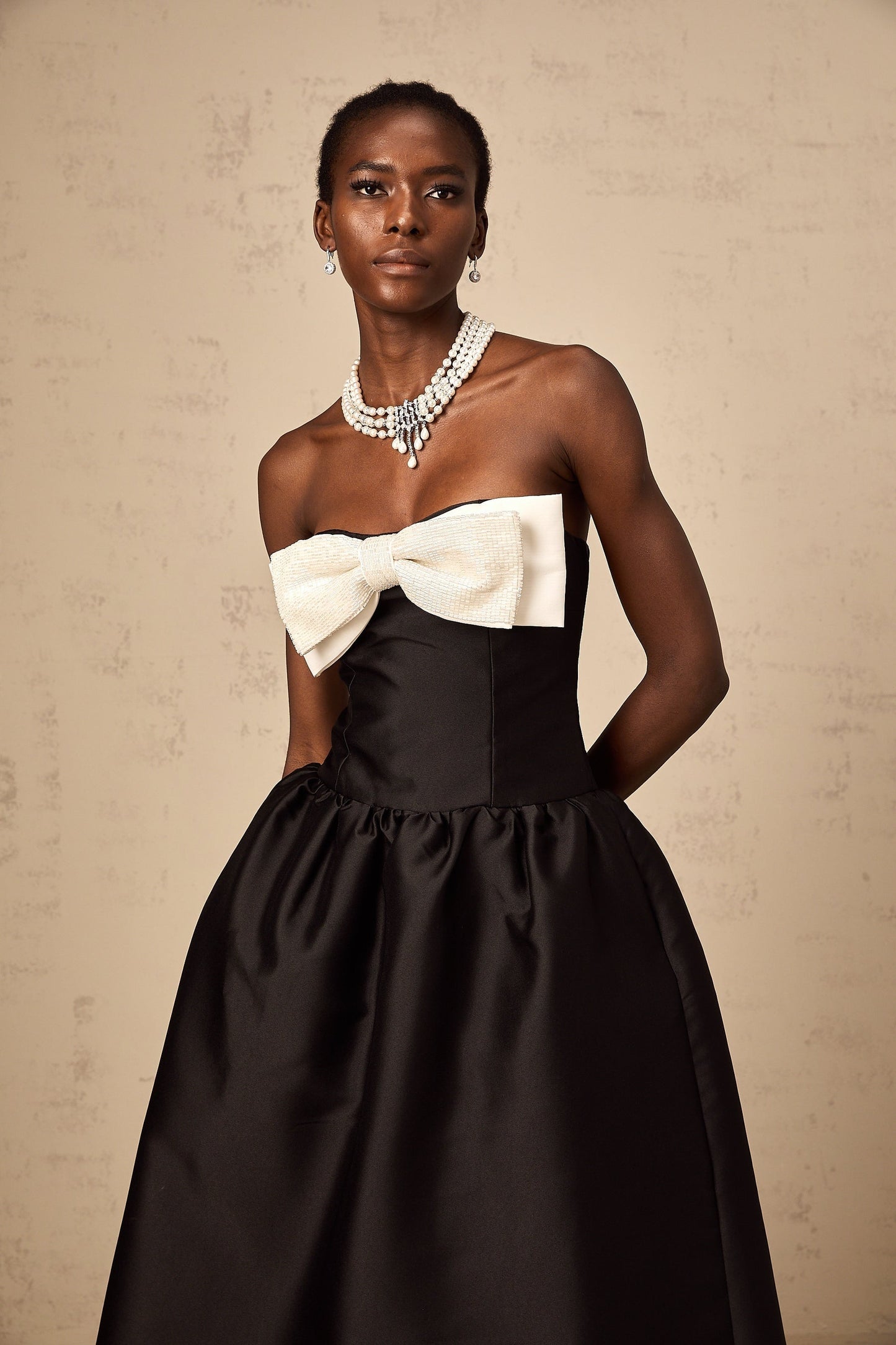 A black offshoulder midi dress made of georgette fabric featuring a bowknot detail