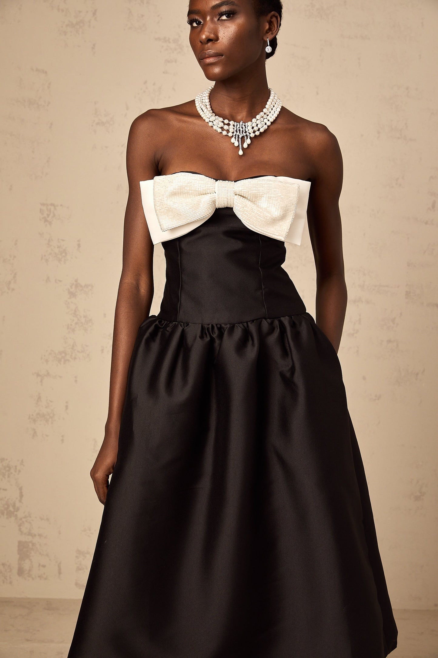 A black offshoulder midi dress made of georgette fabric featuring a bowknot detail