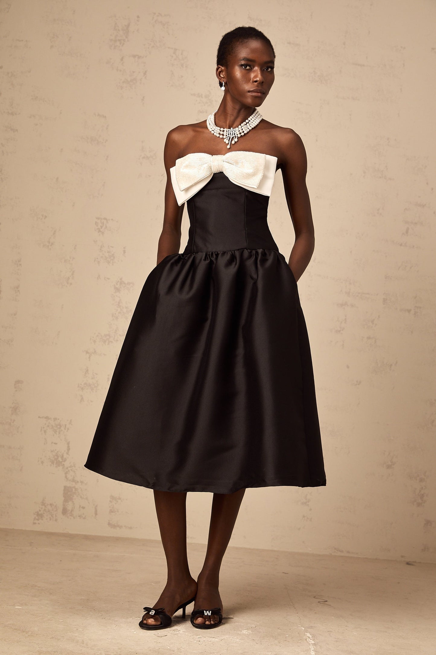 A black offshoulder midi dress made of georgette fabric featuring a bowknot detail