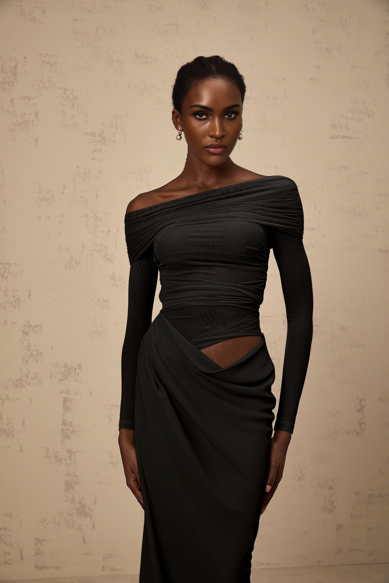 A black offshoulder midi dress with semisheer fabric on a mannequin or model showing the flowy silhouette and elegant design