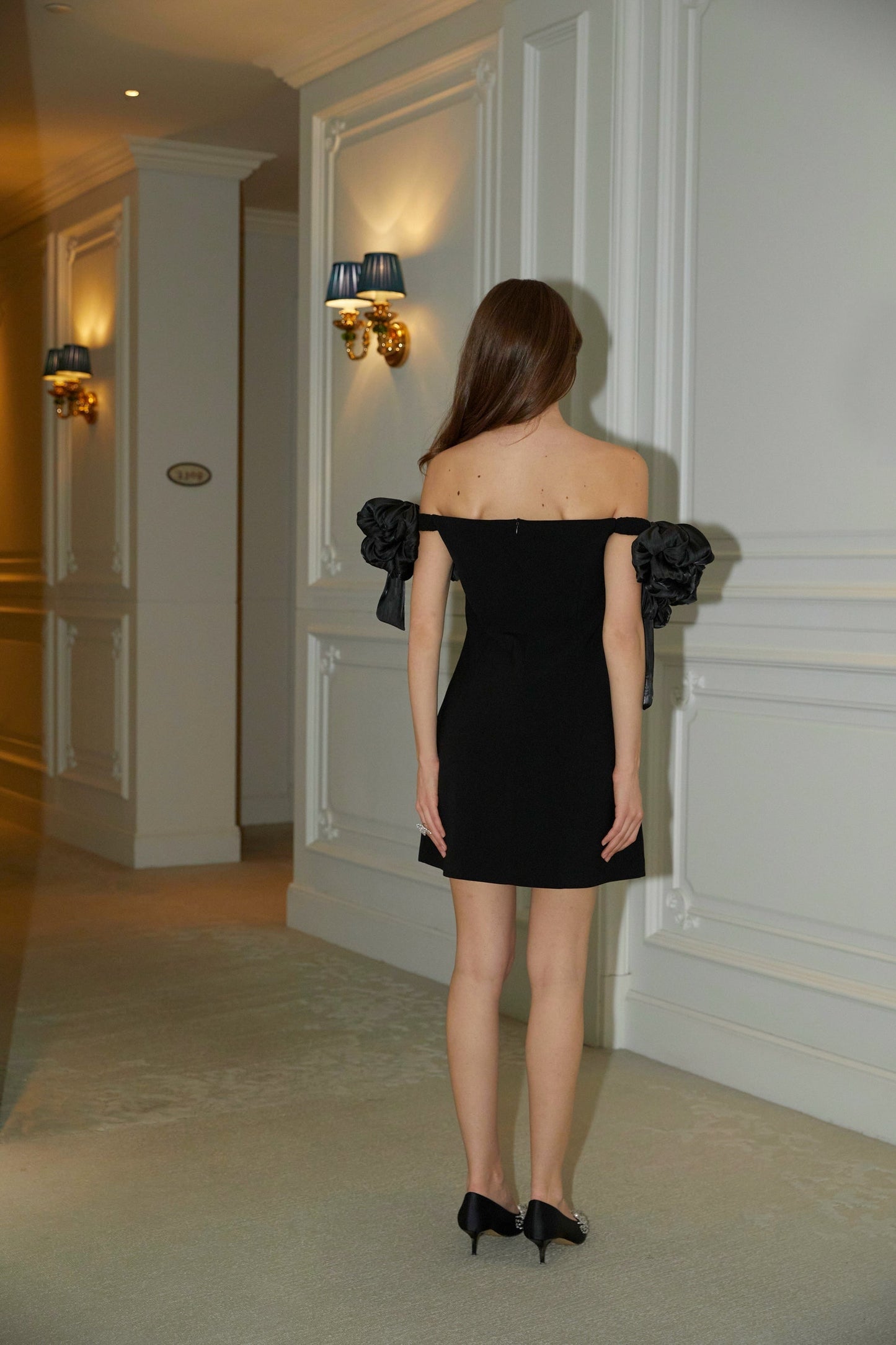A black offshoulder mini dress with floral details named Erica worn by a model against a plain background