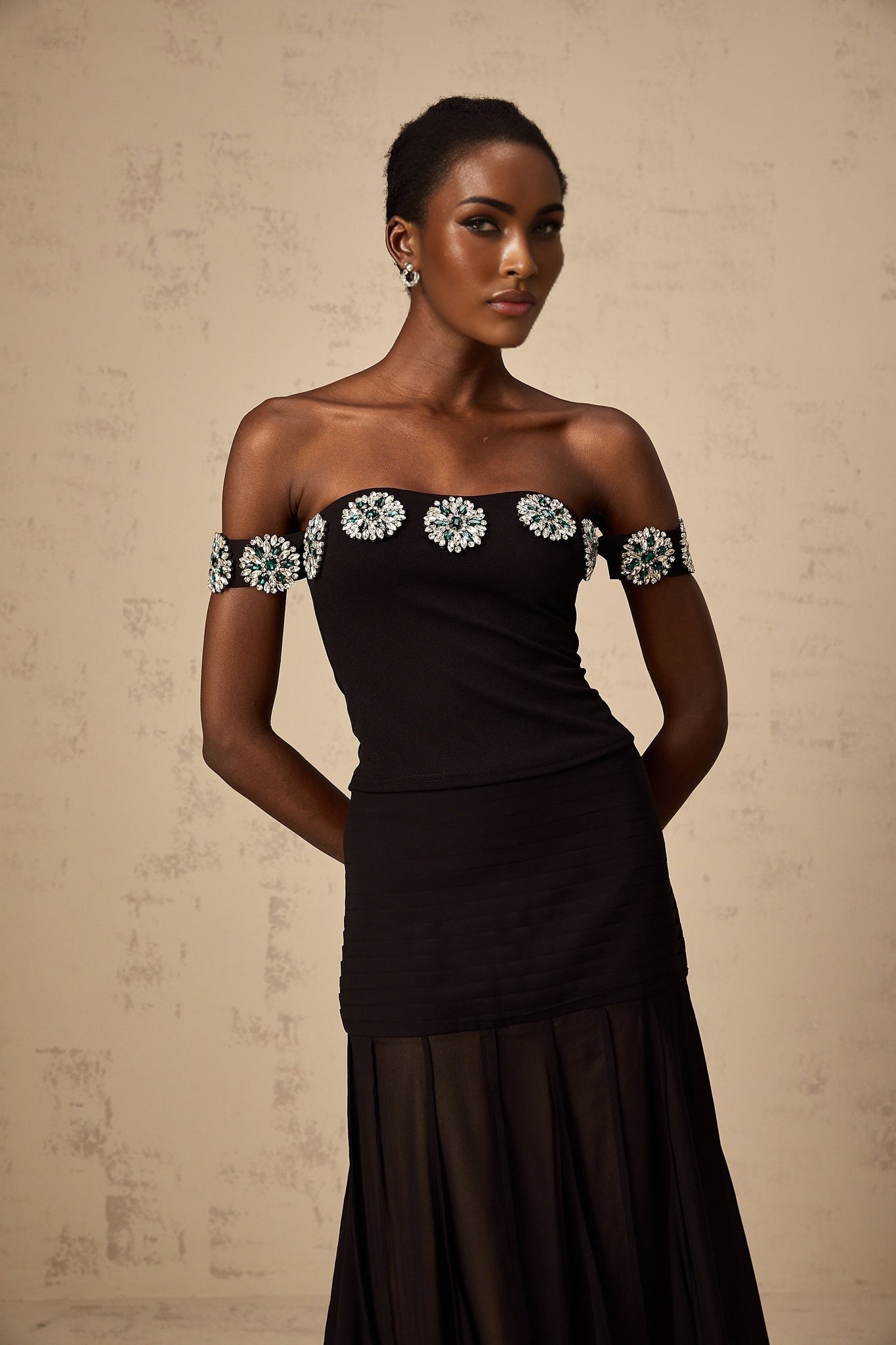 A black offshoulder top with embellishments named Carina featuring a sleek design and decorative details on the fabric
