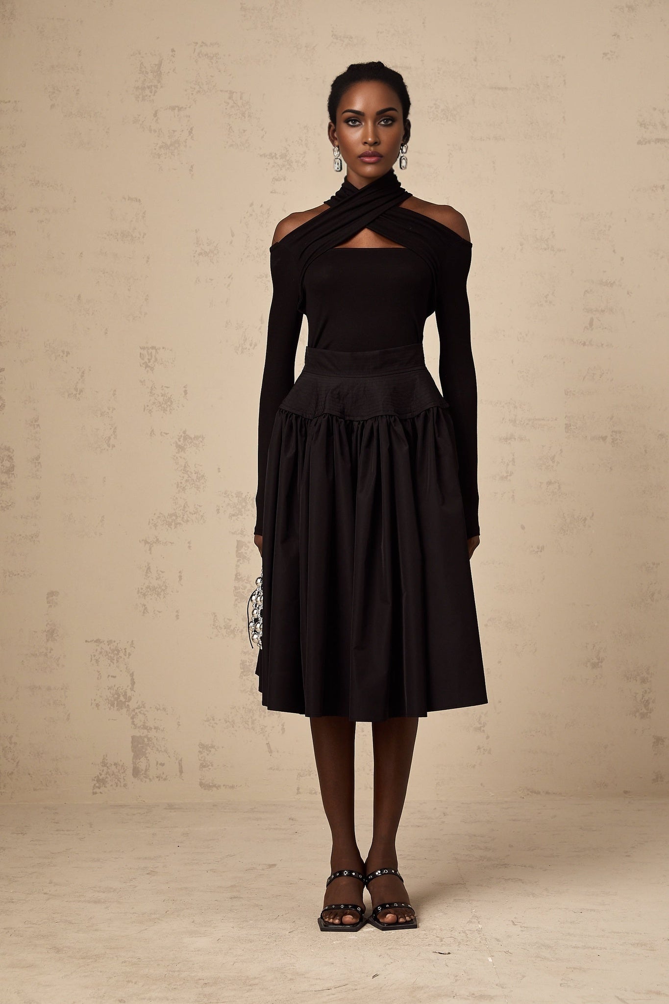 A black pleated midi skirt with a flared silhouette called Pauline
