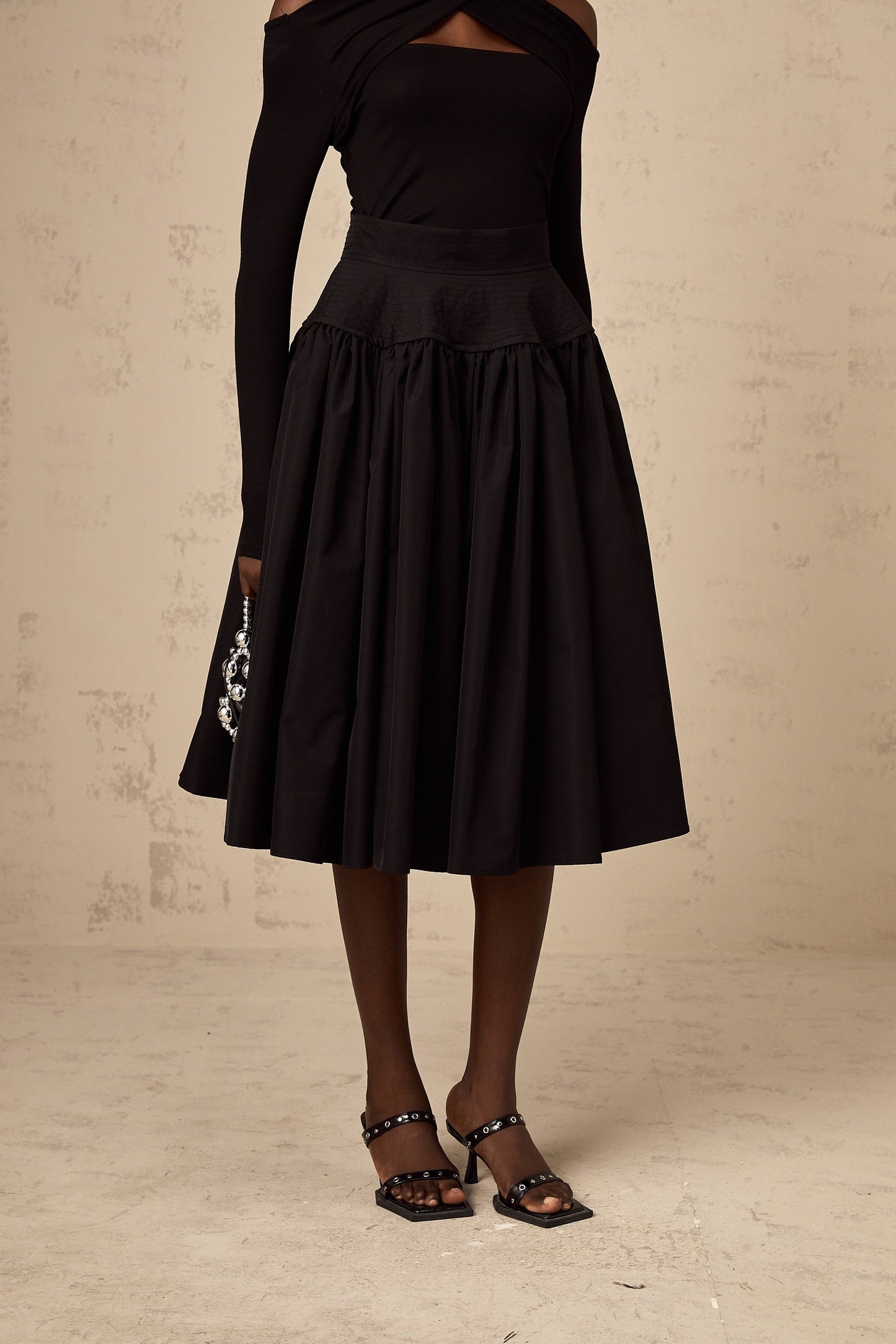 A black pleated midi skirt with a flared silhouette named Pauline