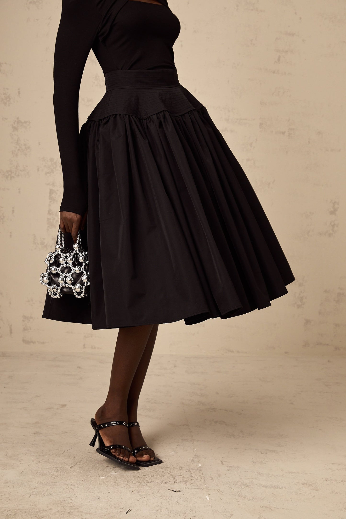A black pleated midi skirt with a flared silhouette named Pauline