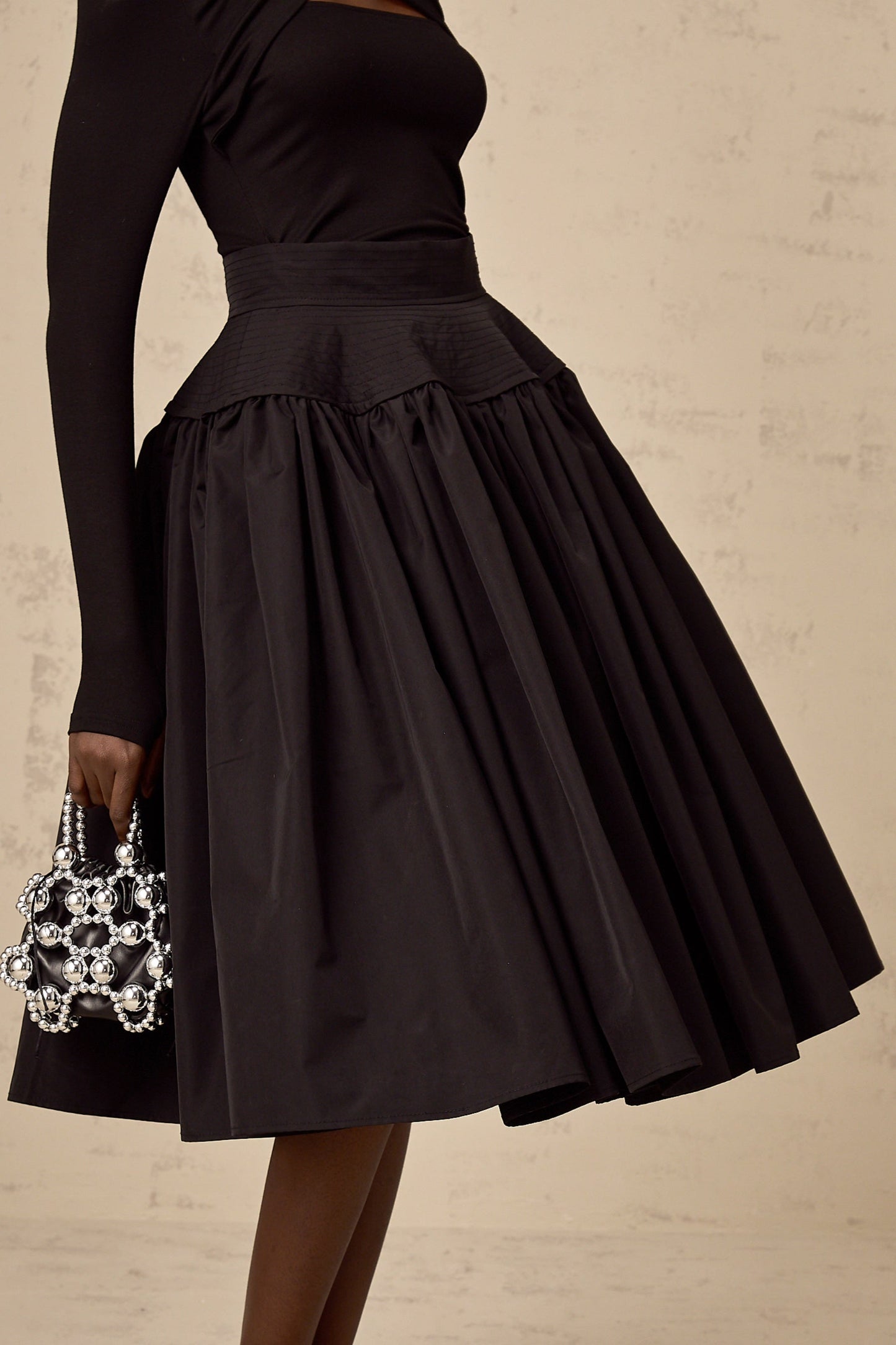 A black pleated midi skirt with a flared silhouette named Pauline