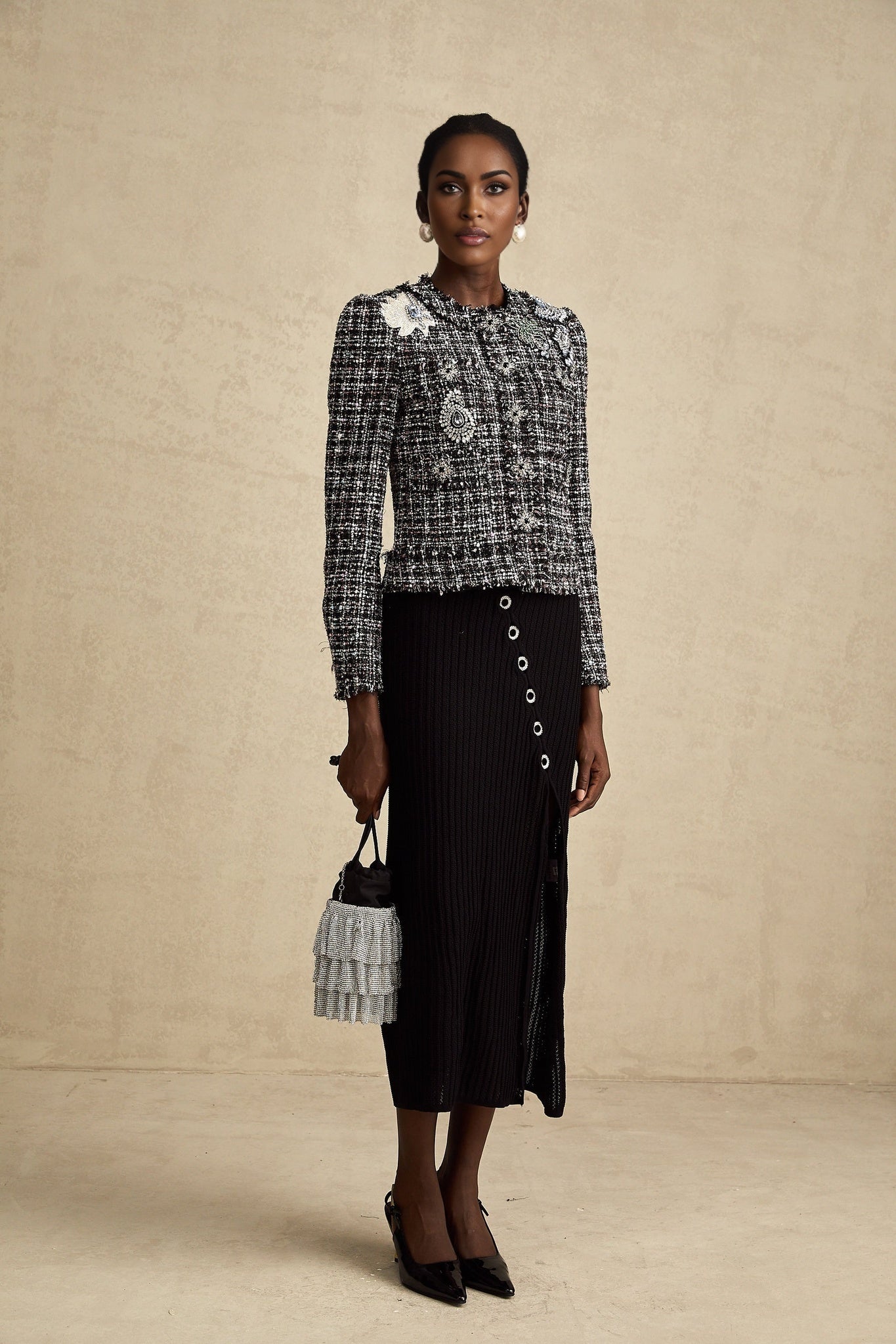 A black tweed jacket with frayed edges and a checked pattern worn by a model named Justine