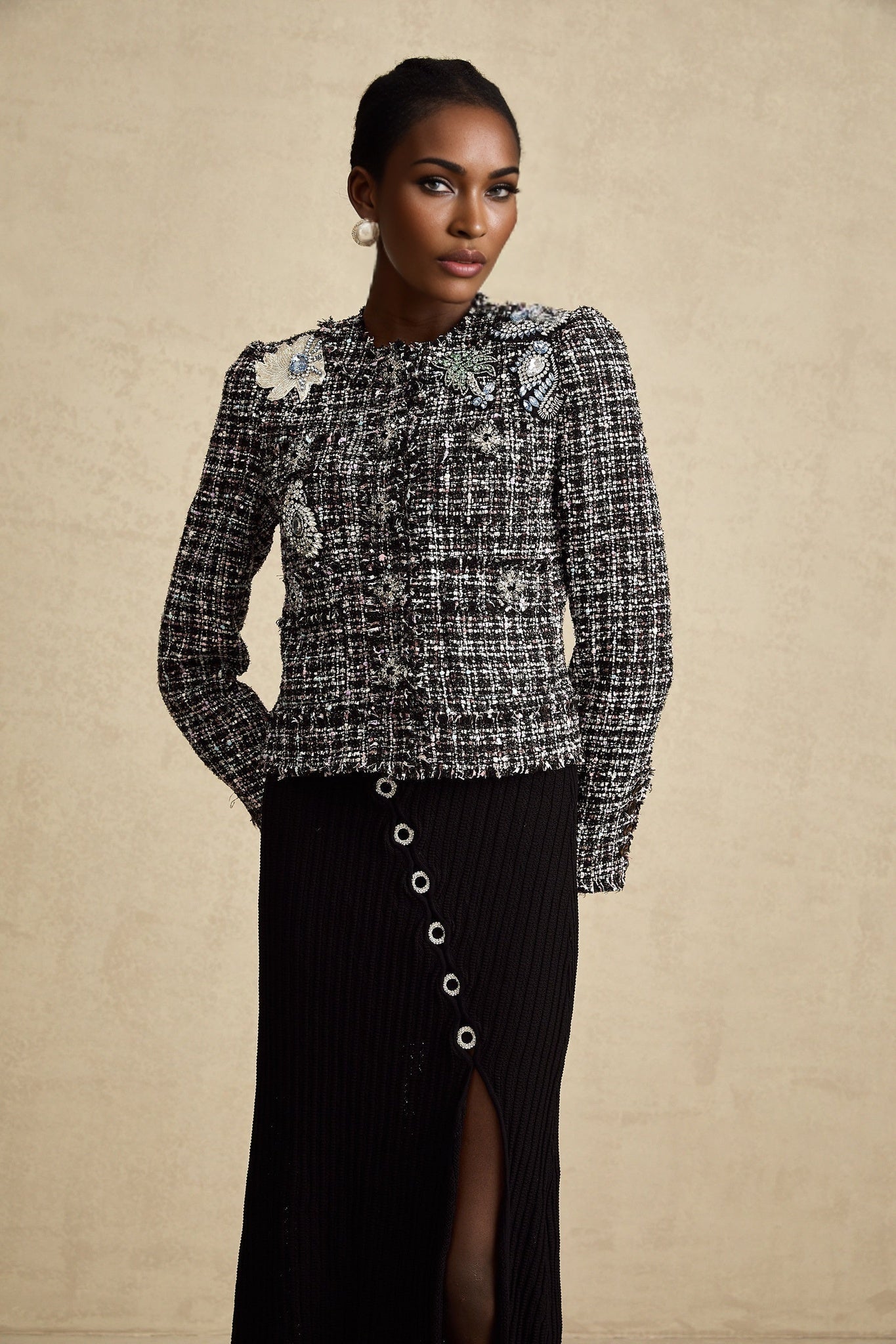 A black tweed jacket with frayed edges and a checked pattern worn by a model named Justine