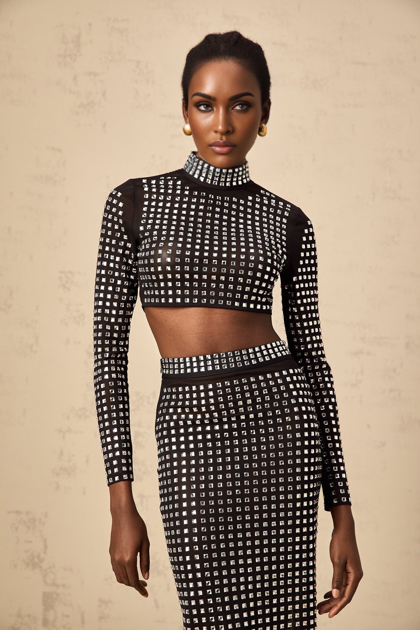 A black twopiece outfit consisting of a mesh top and skirt adorned with rhinestones creating a sparkly effect The set features a sleeveless top and a fitted skirt both made from sheer black fabric embellished with glittering rhinestones for an elegant evening look