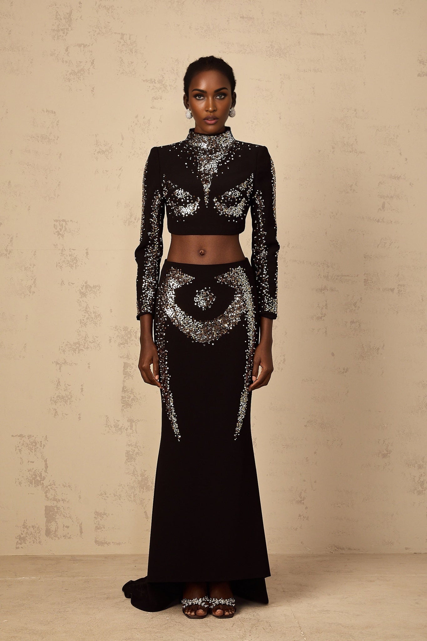 A black twopiece outfit featuring a top and skirt set covered in shimmering sequins The ensemble is called Mahault and has an embellished design for a glamorous look