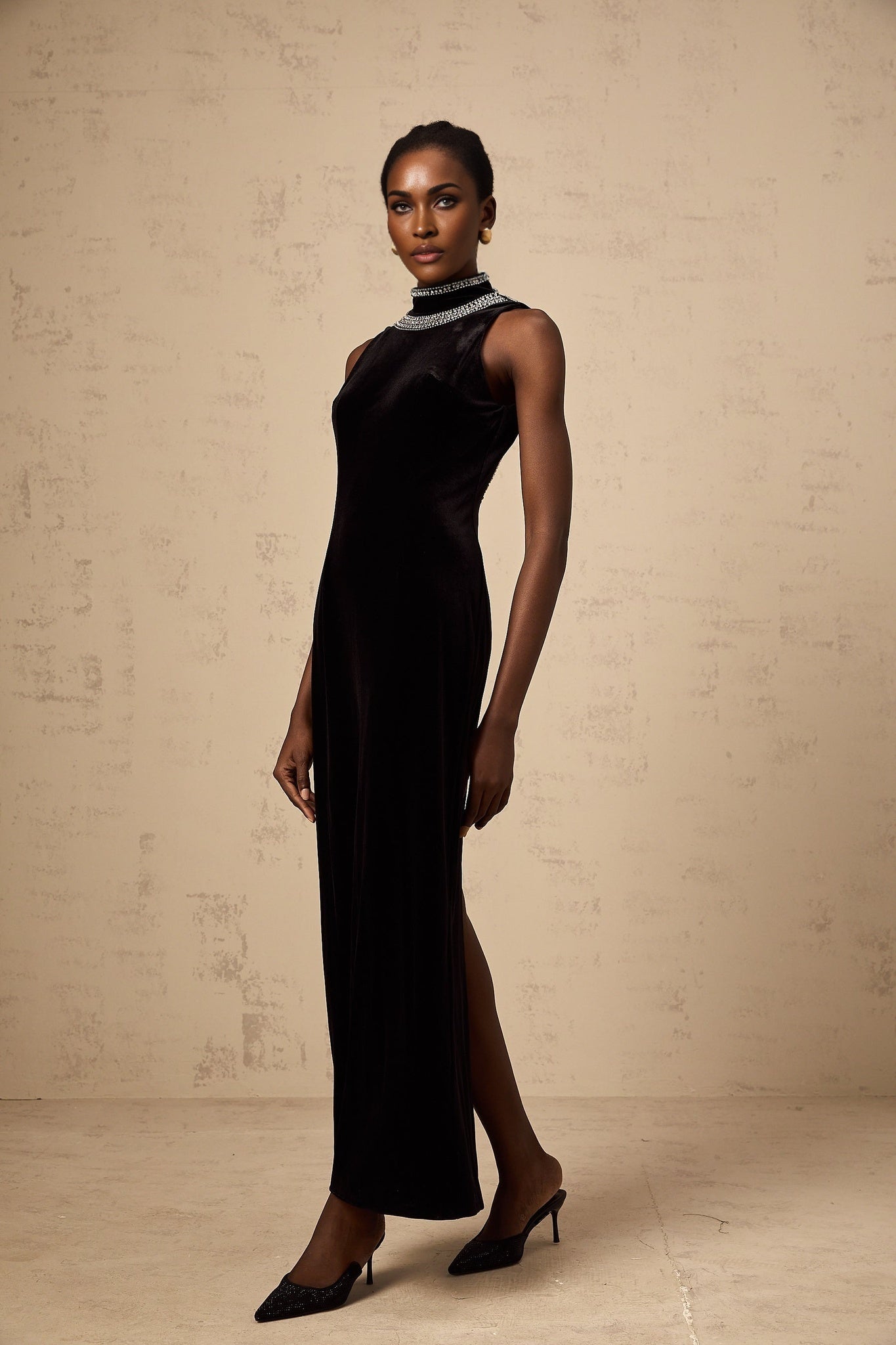 A black velvet floorlength gown adorned with sparkling crystal embellishments featuring a sleek silhouette and elegant design