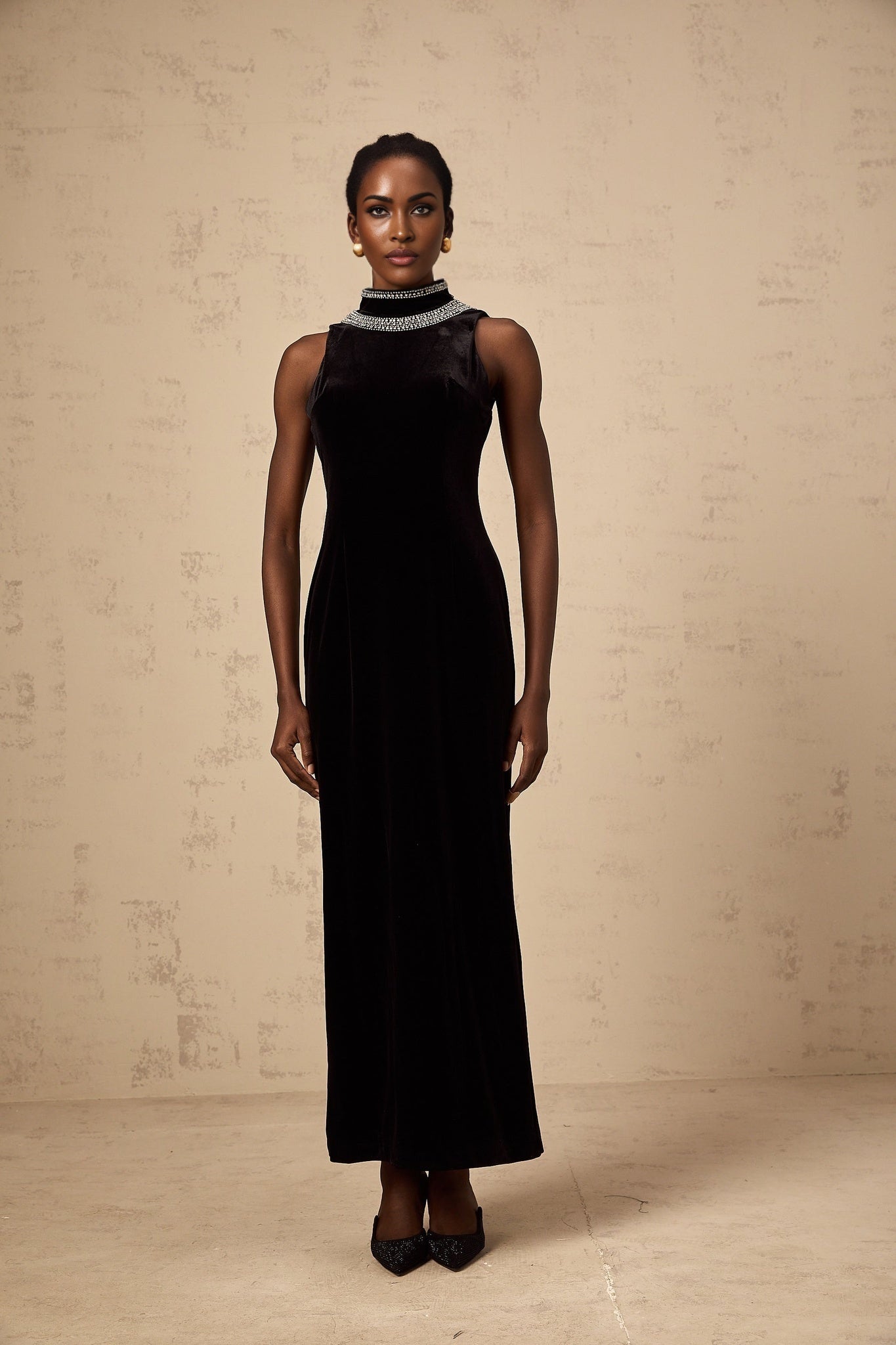 A black velvet gown adorned with crystal embellishments featuring a long silhouette and elegant design