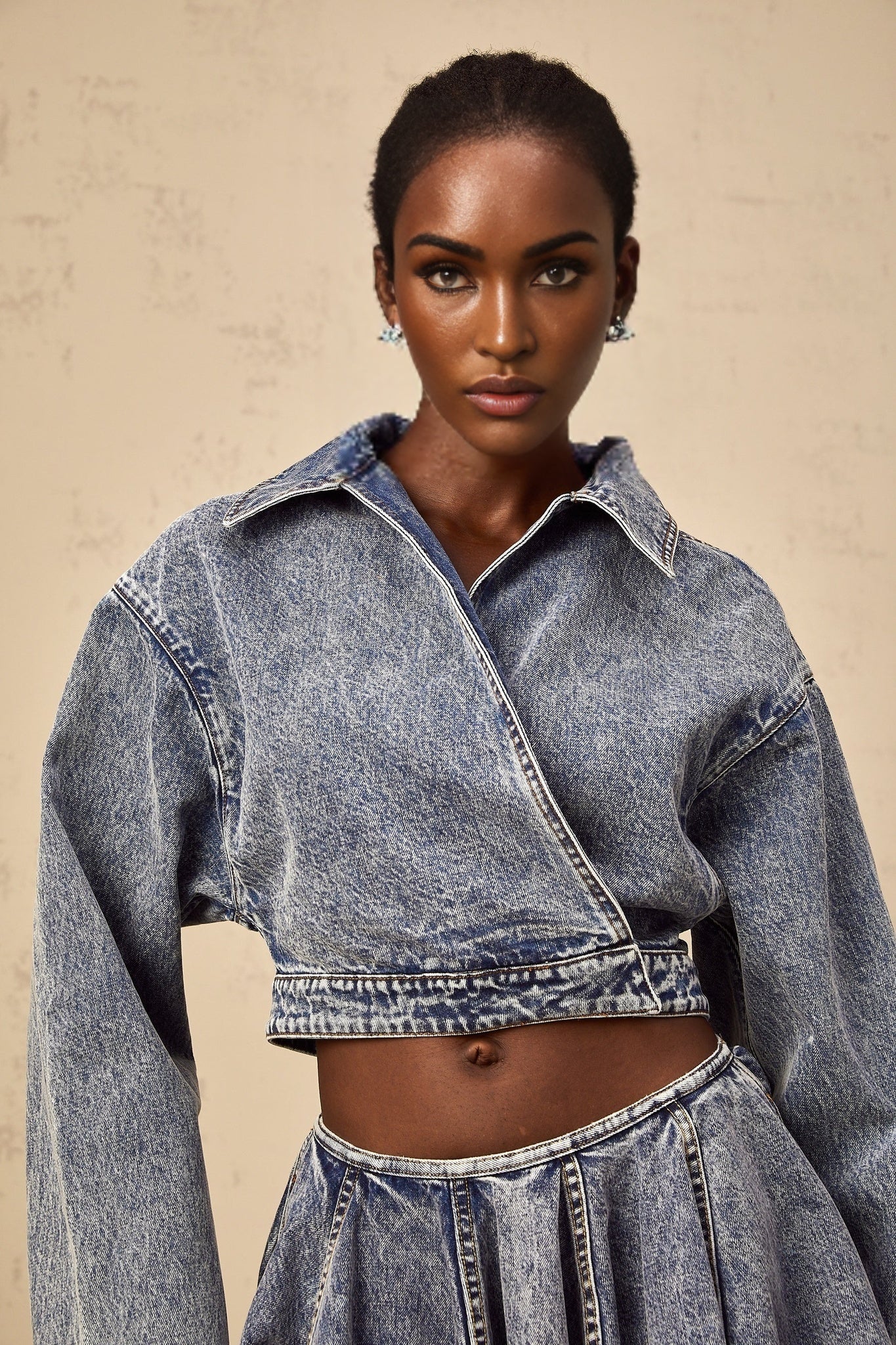 A blue cropped denim jacket with an asymmetrical design featuring a distinctive cut and style named Doriane