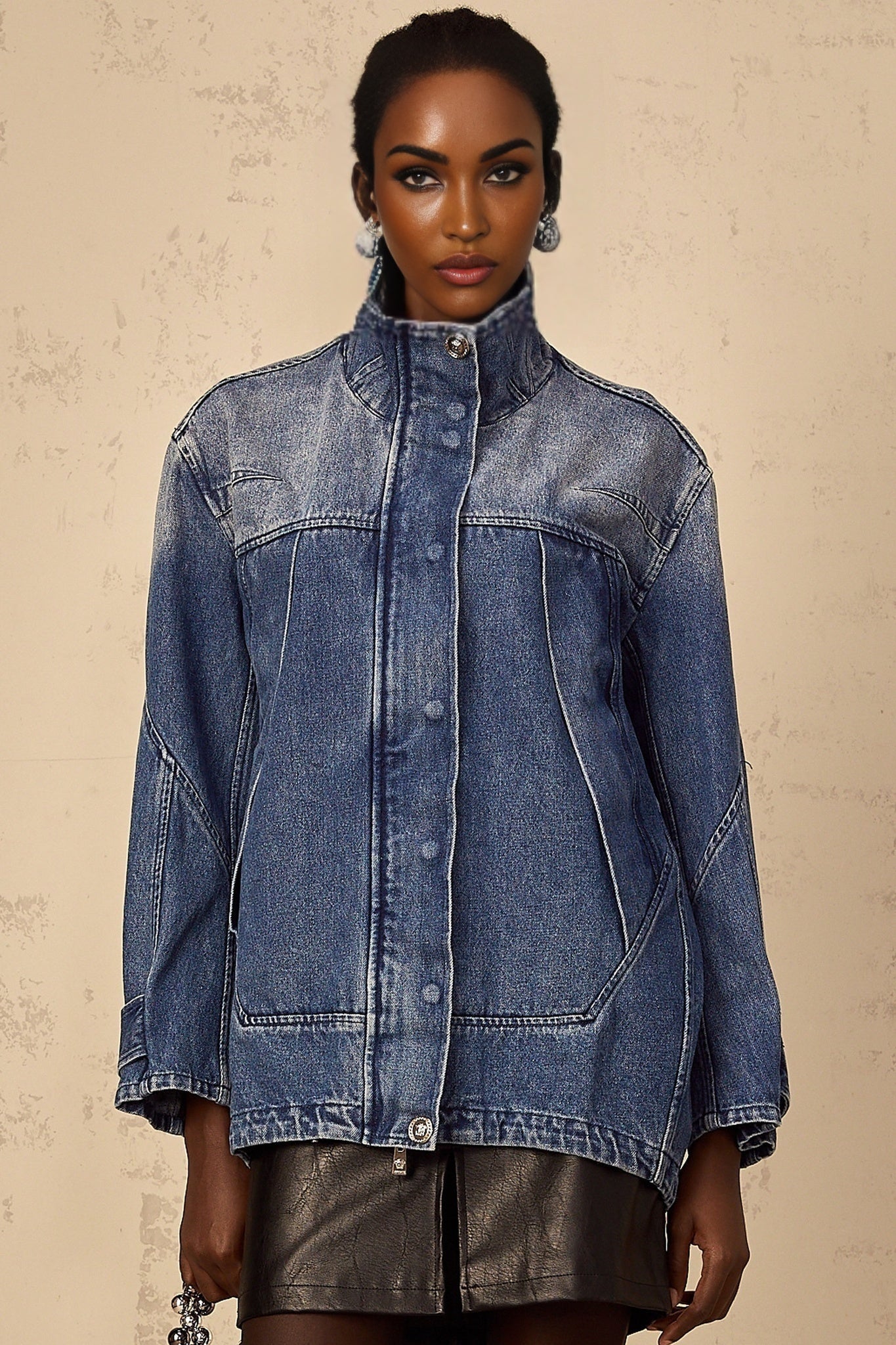 A blue denim jacket with patchwork design and loose fit worn by a model named Geraldine
