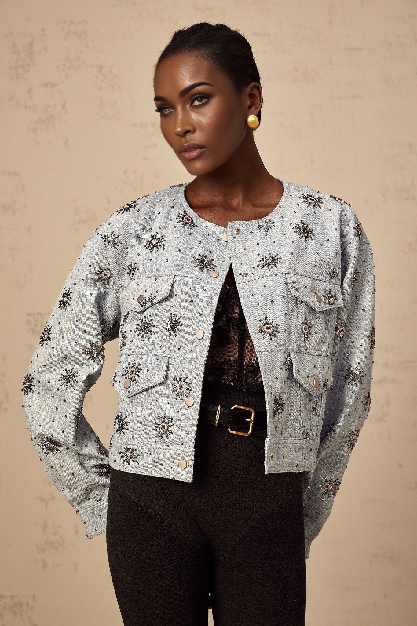 A blue denim jacket with studded sun motifs and decorative embellishments featuring a distressed look and visible stitching details