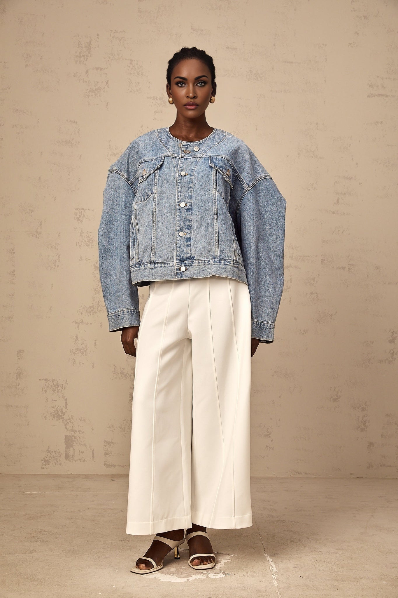 A blue denim jacket without a collar featuring a relaxed fit and button front closure