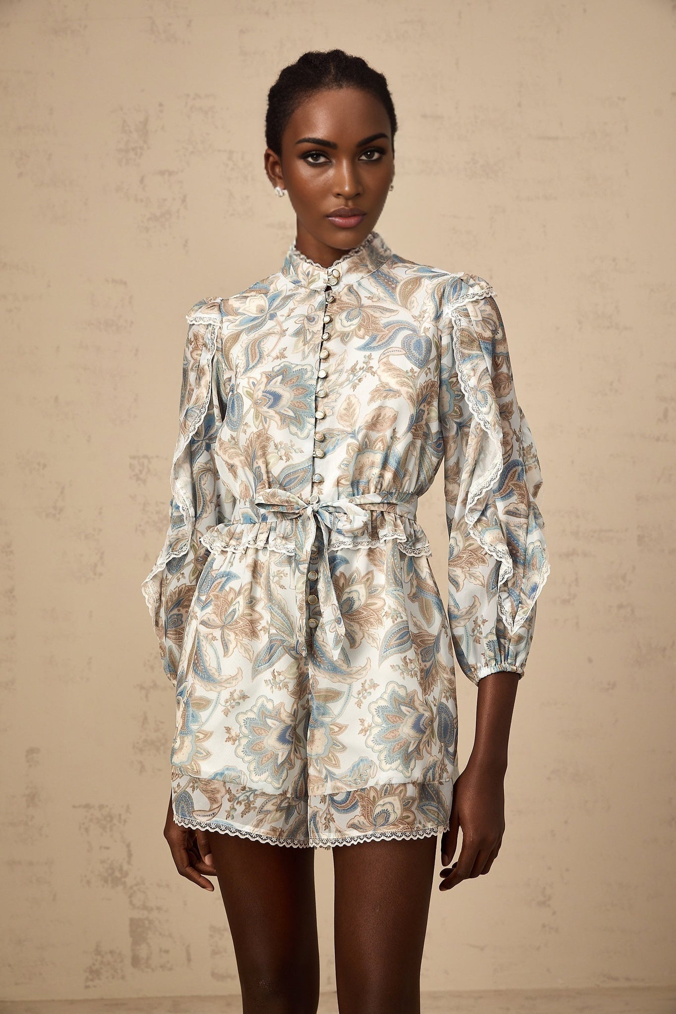 A blue floral print jumpsuit with lace trim and ruffled details named Eugenie