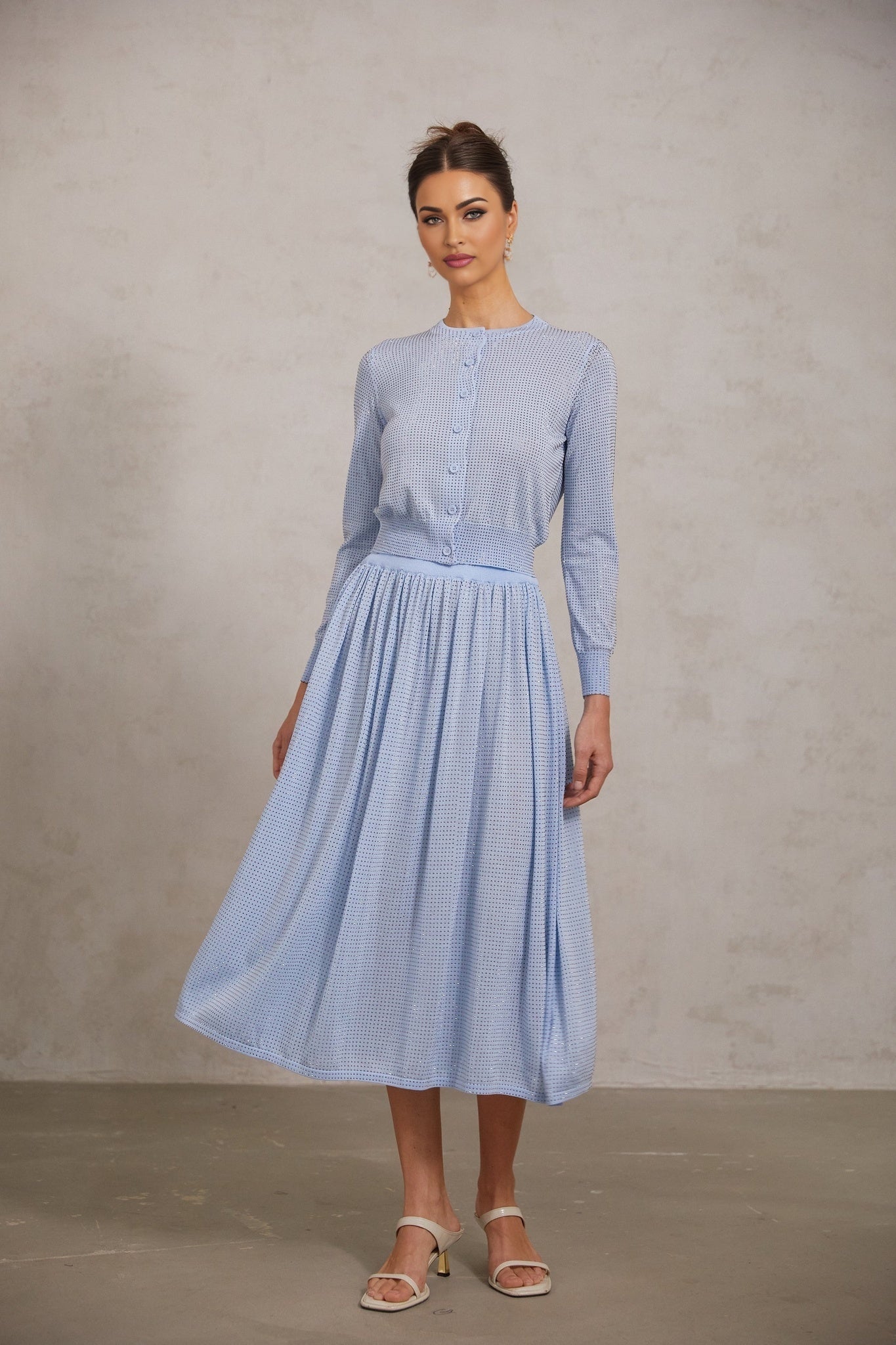 A blue knitted two piece outfit consisting of a top and skirt adorned with rhinestone embellishments