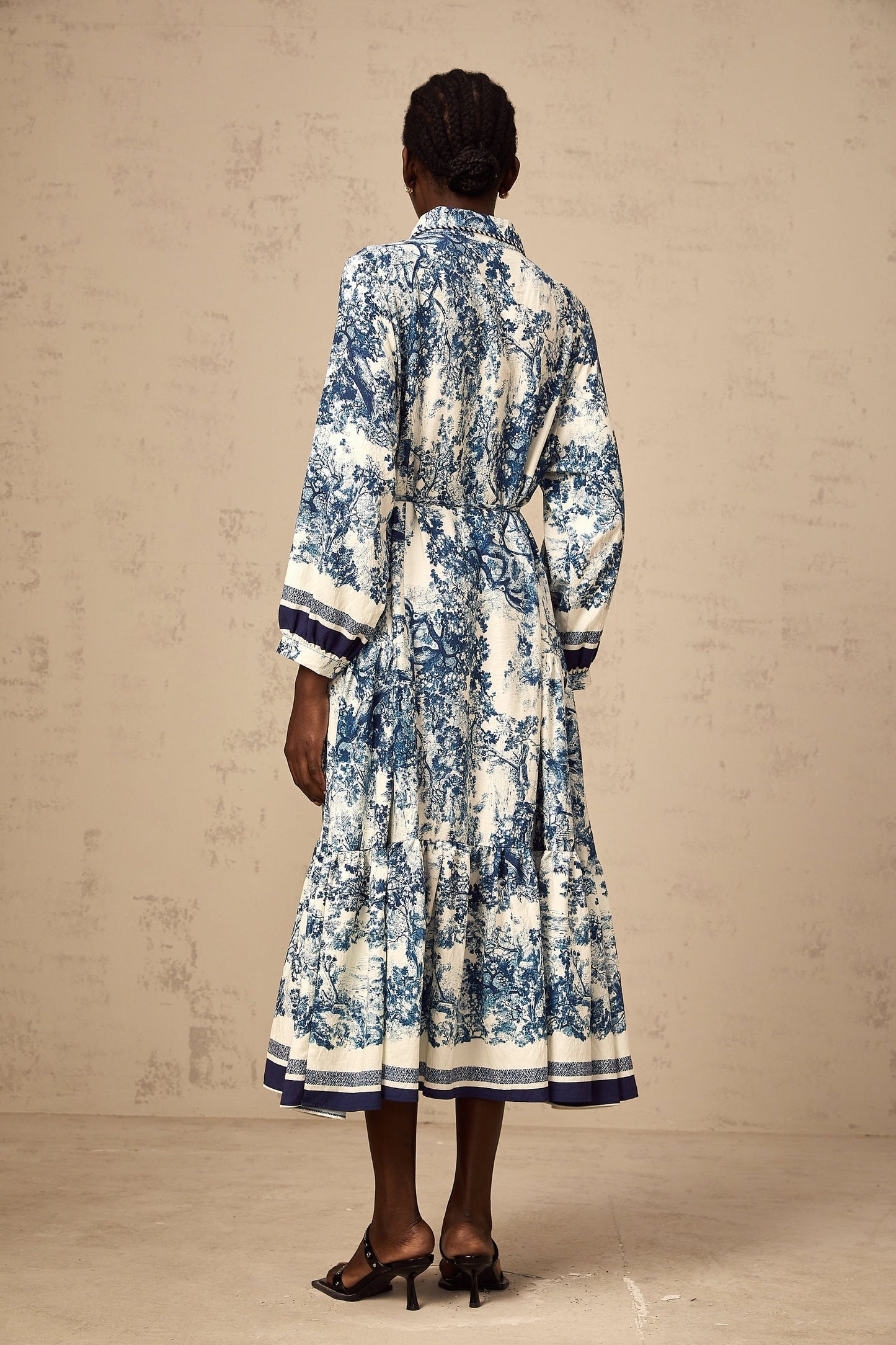 A blue midi dress with a graphic print pattern named Adelaide worn by a model standing against a plain background