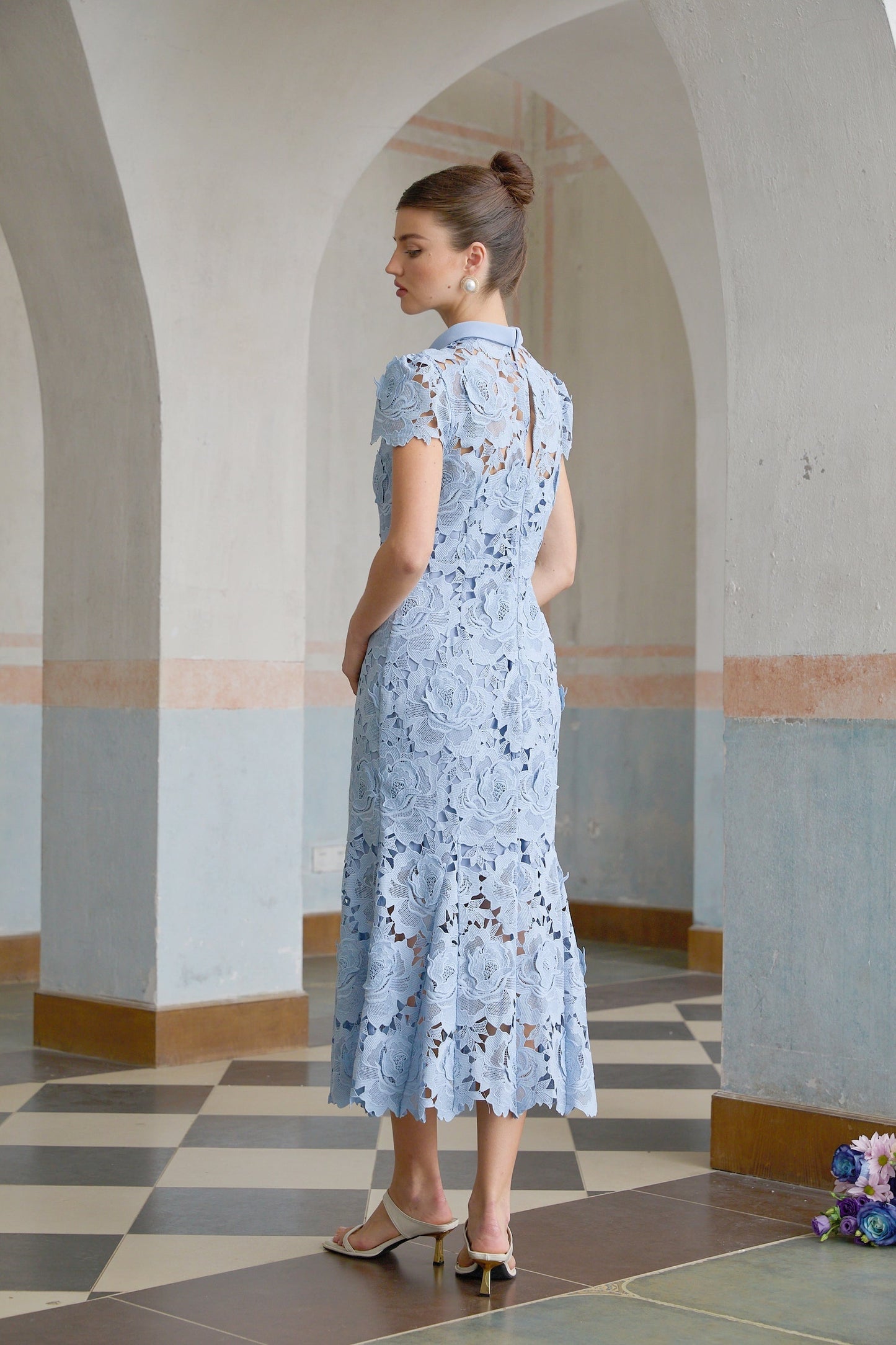 A blue midi dress with delicate floral lace applique details covering the bodice and skirt creating an elegant and romantic look