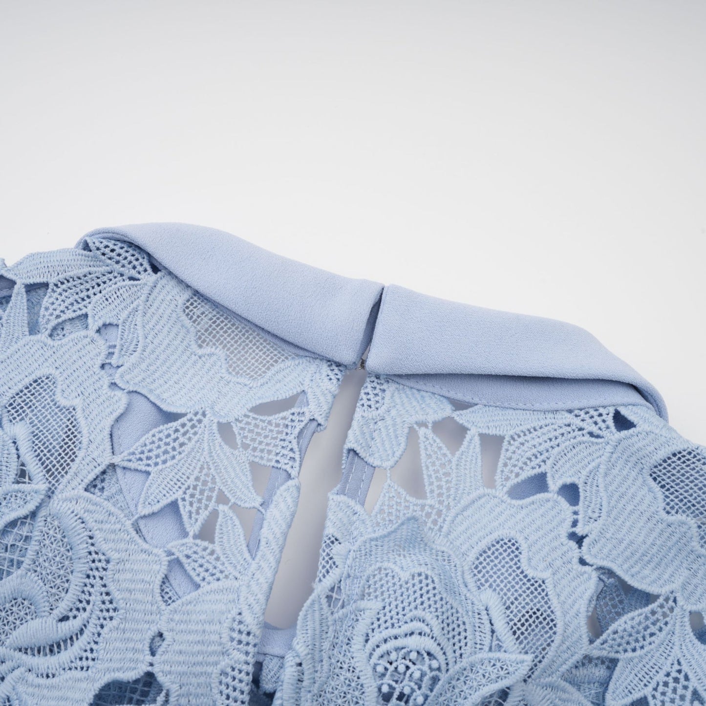 A blue midi dress with floral lace appliques and a delicate floral pattern throughout the fabric