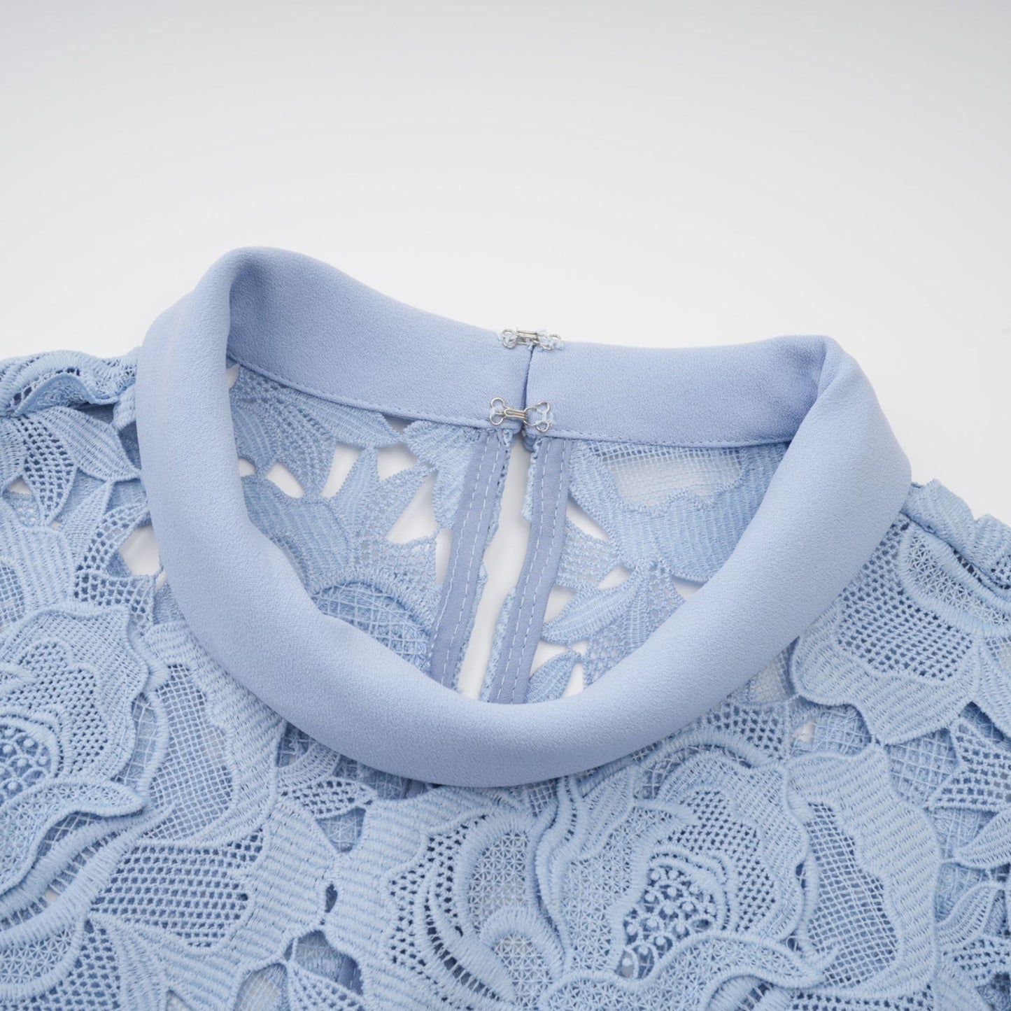 A blue midi dress with floral lace appliqués and a delicate floral pattern throughout the fabric