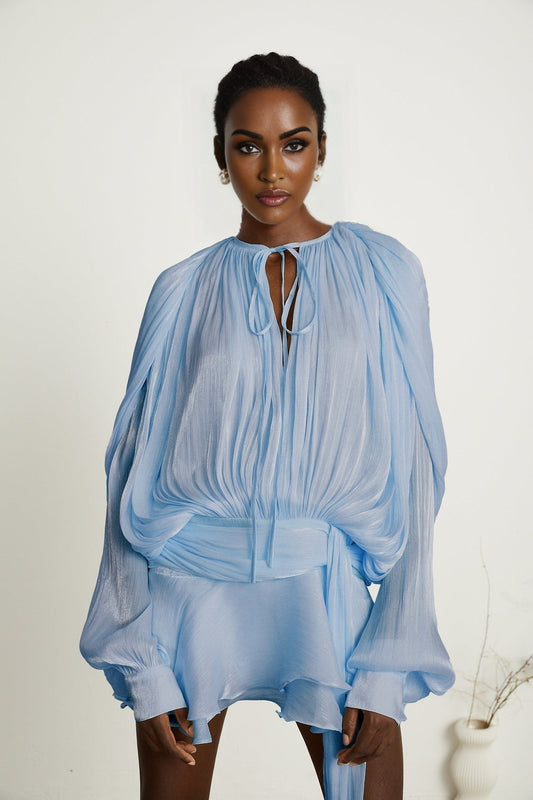 A blue mini dress with full pleats and ruffles called the Eugenie featuring a short hemline and feminine details