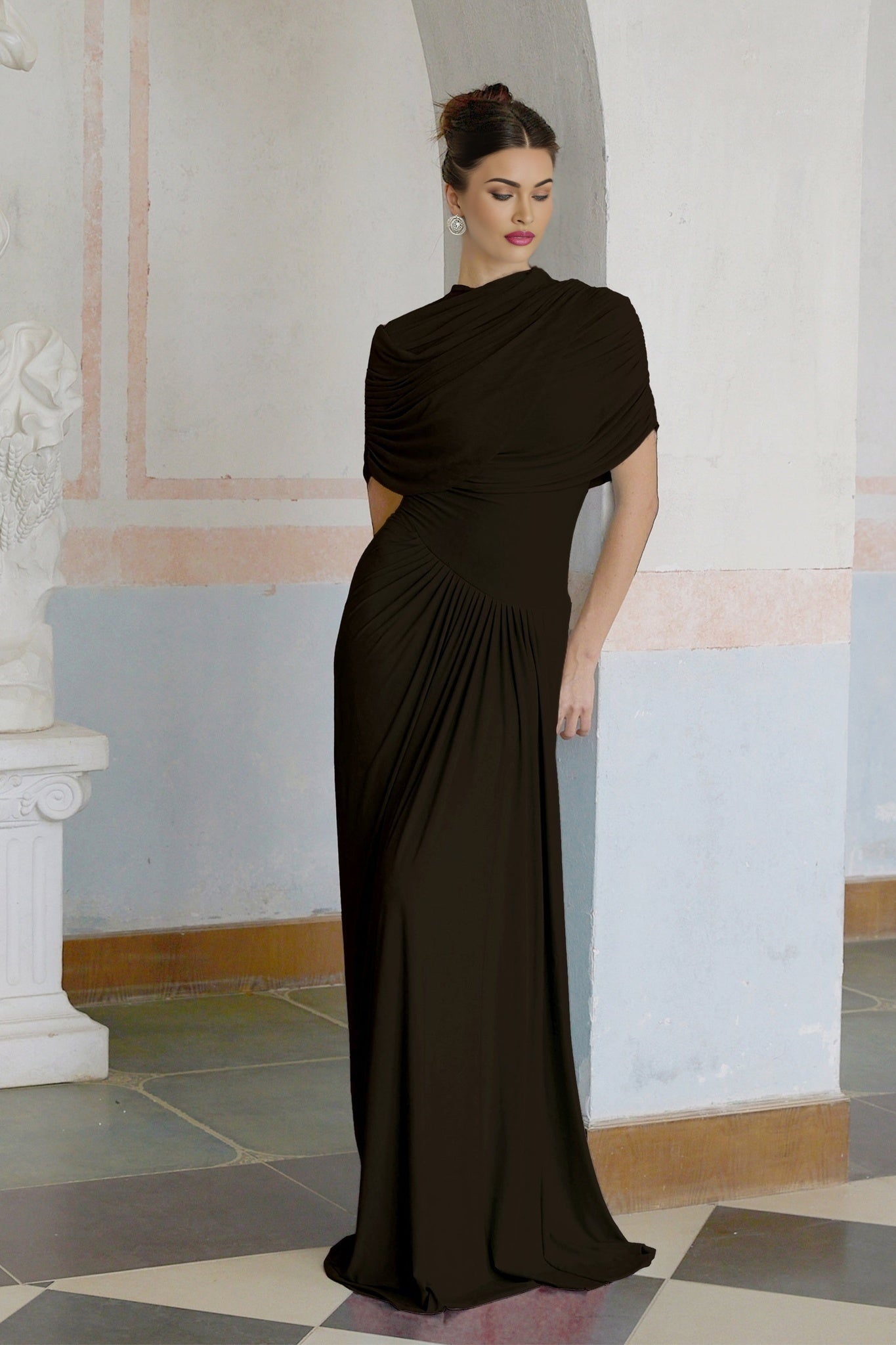 A brown asymmetric maxi dress with pleated details and a long flowing skirt worn by a female model