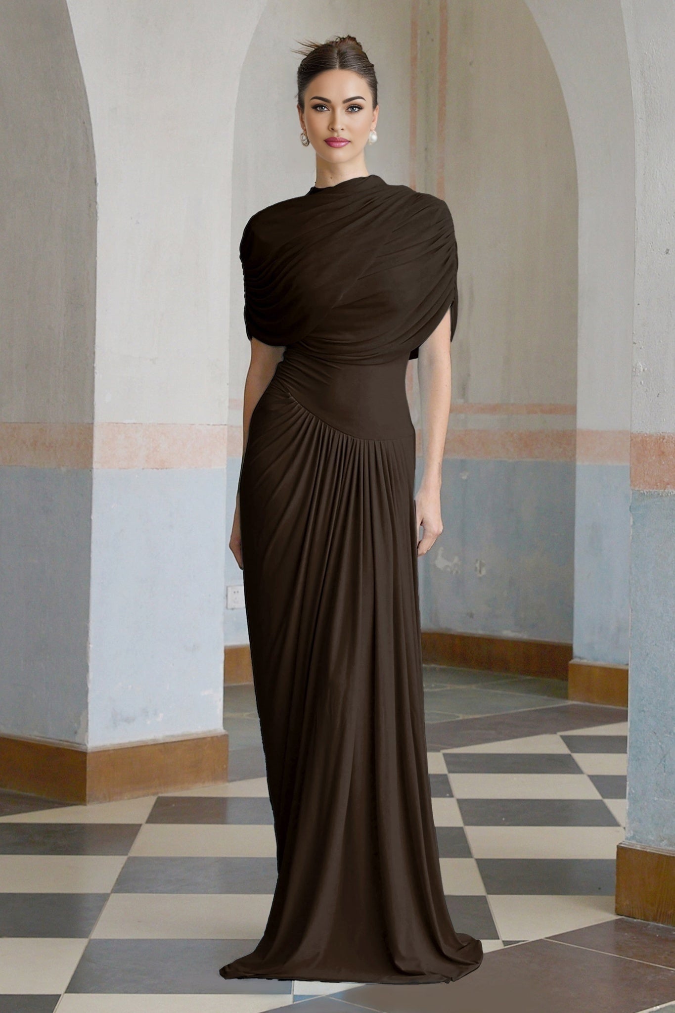 A brown asymmetric maxi dress with pleats worn by a model standing against a plain background