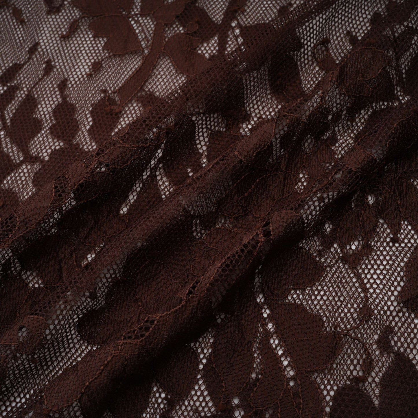 A brown flared midi dress made of chantilly lace named Sylvie featuring delicate floral patterns and a feminine silhouette