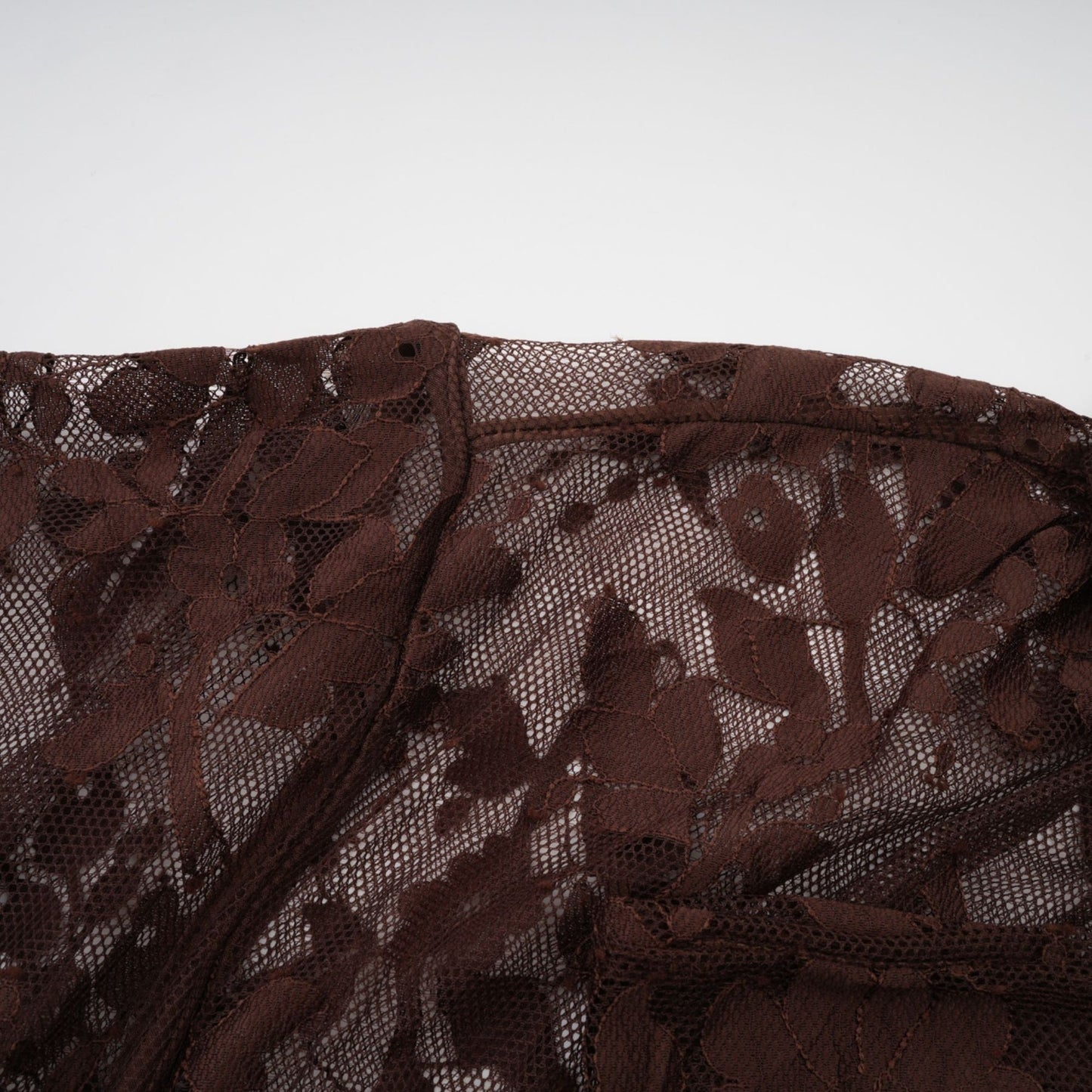 A brown flared midi dress made of chantilly lace named Sylvie hanging on a plain background