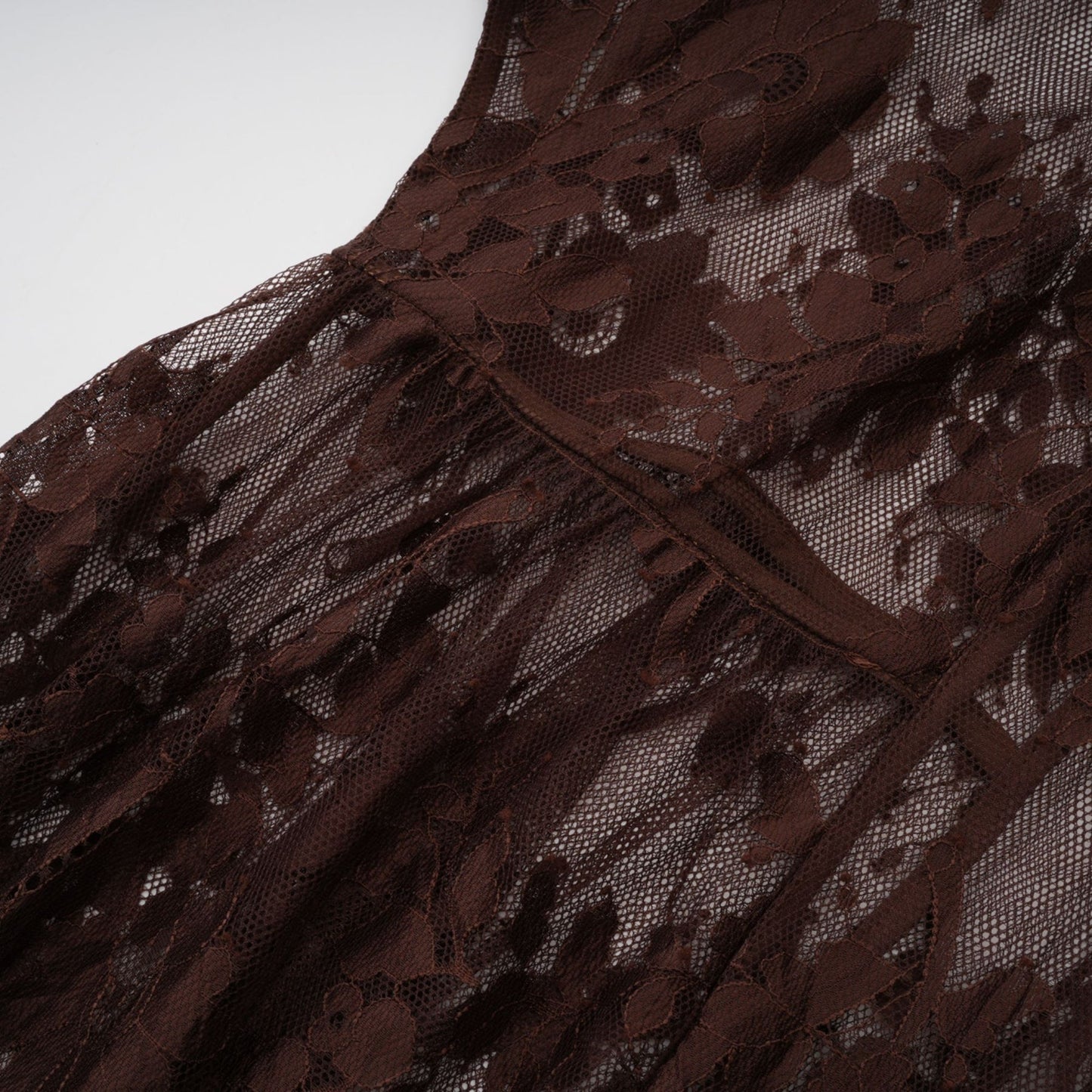 A brown flared midi dress made of chantilly lace named Sylvie on a plain background