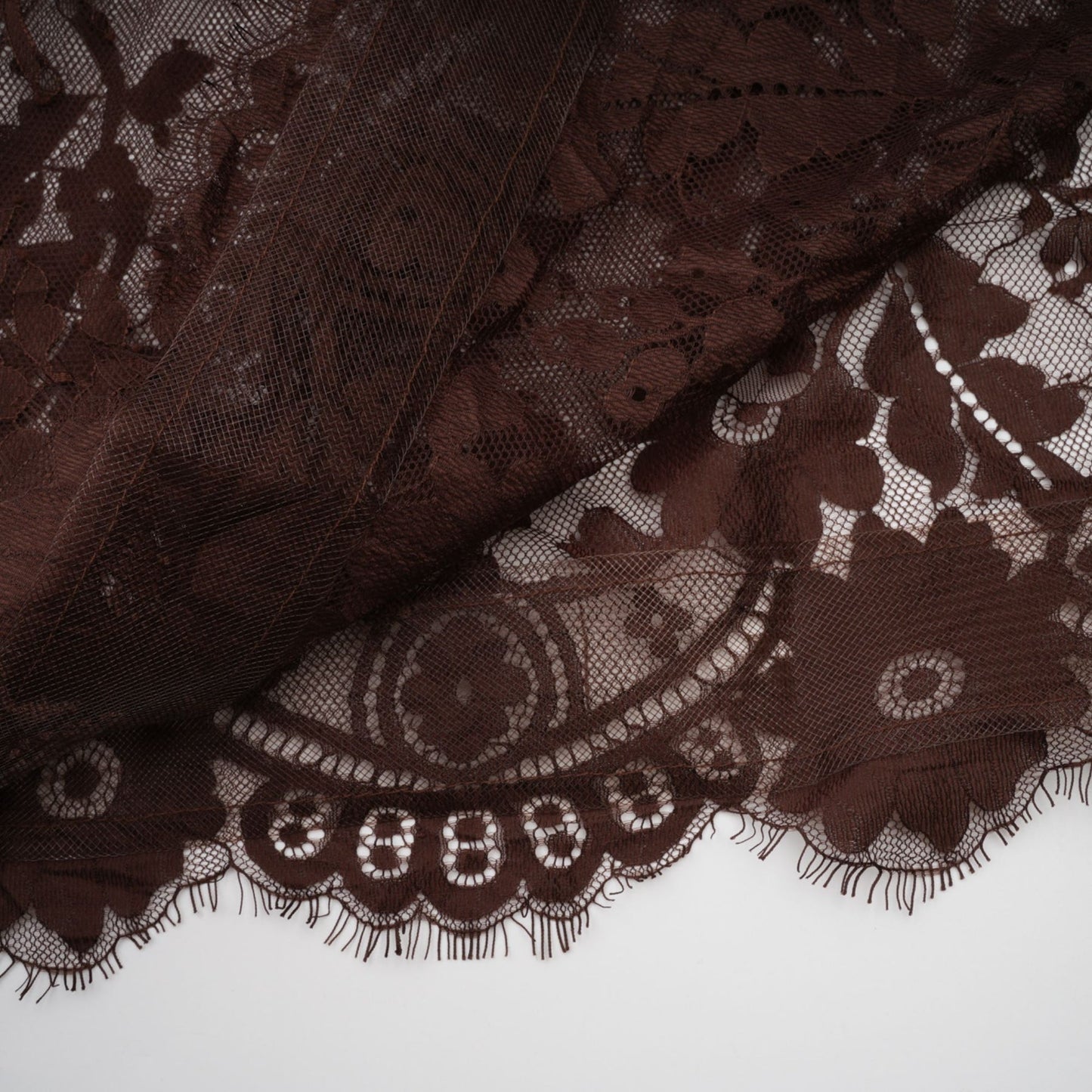 A brown flared midi dress made of chantilly lace named Sylvie worn by a model against a plain background