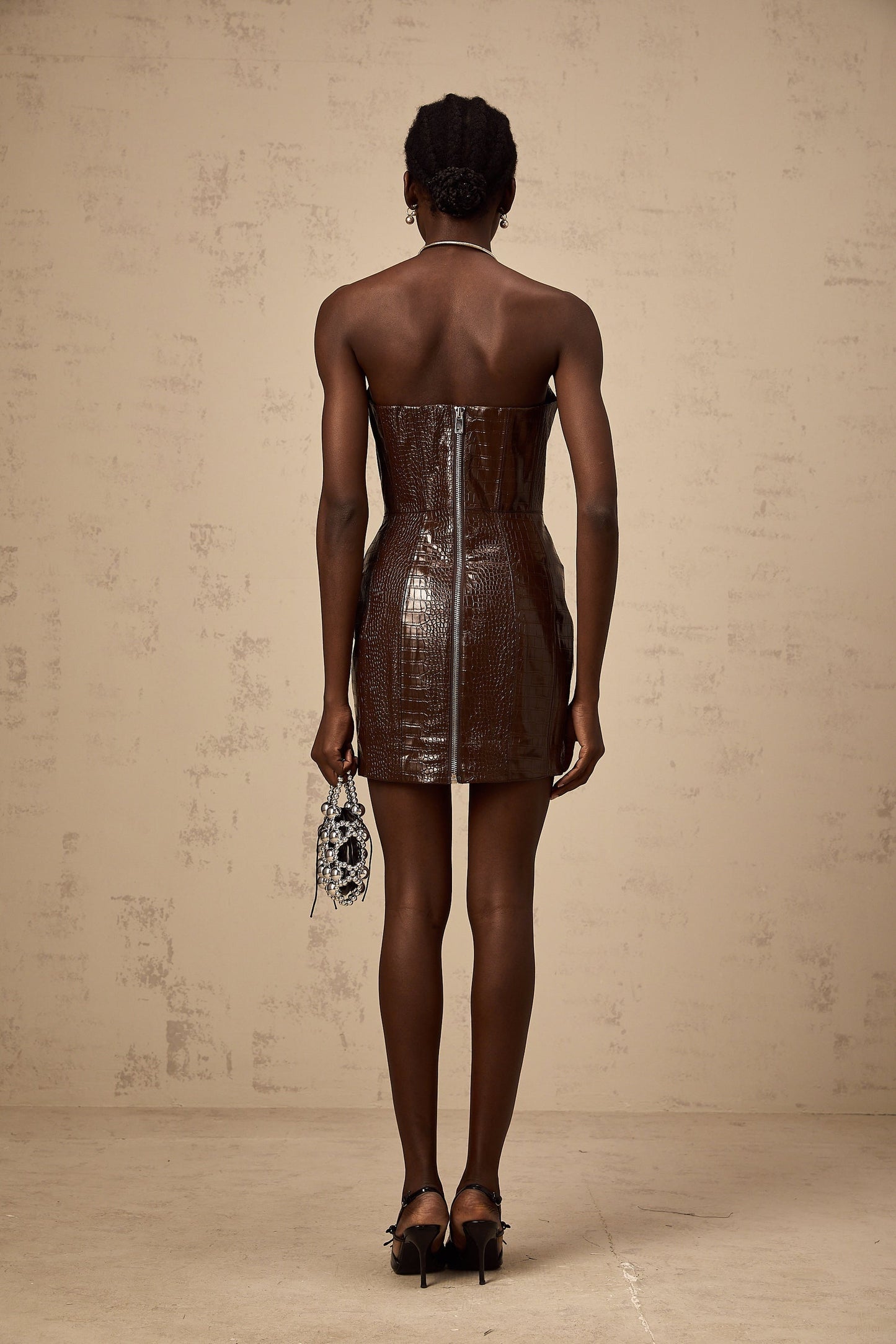 A brown mini dress made of textured leather with a short hemline and sleek design