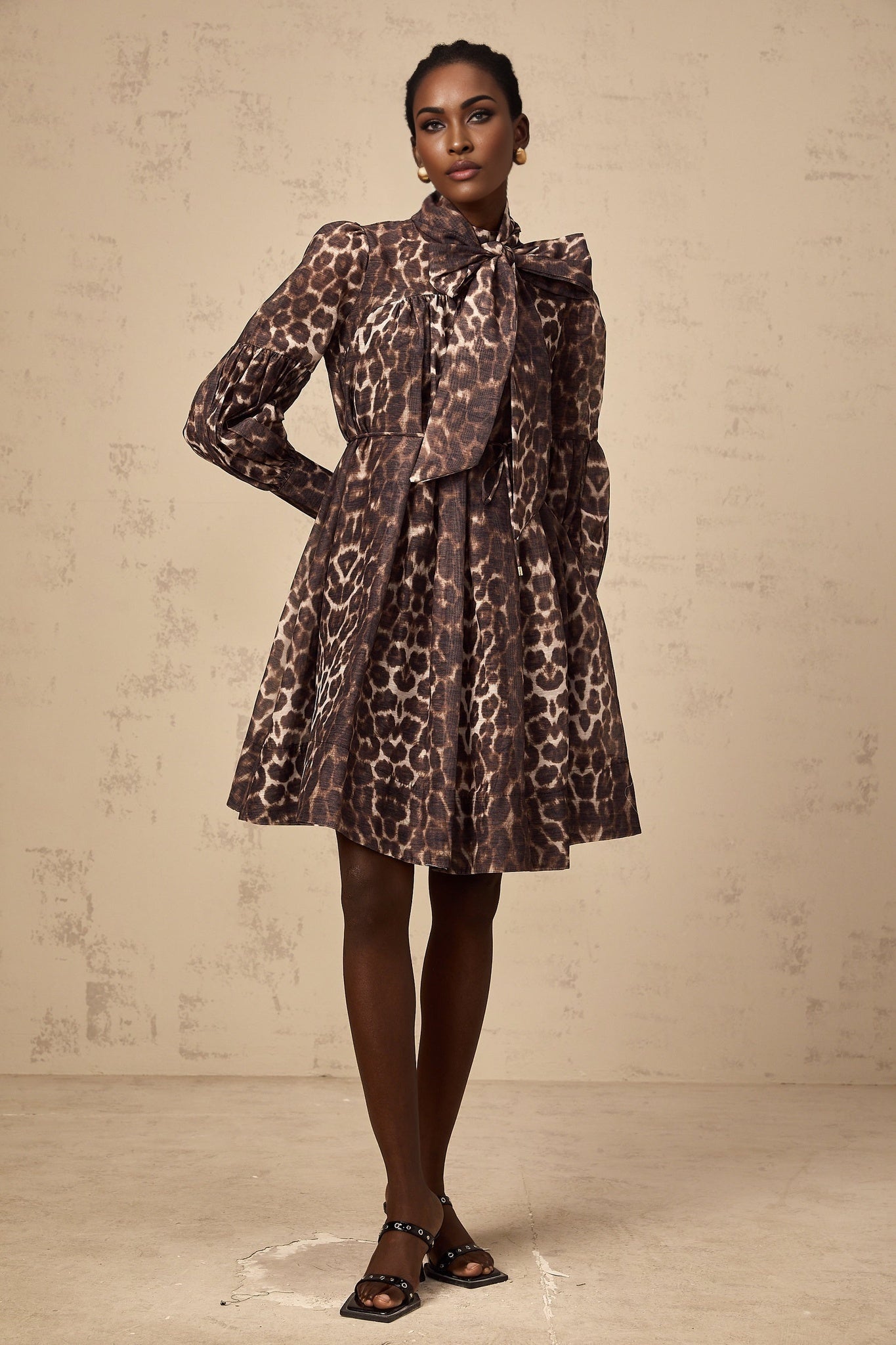 A brown mini dress with leopard print pattern featuring a large bowknot detail and a xylene inspired design