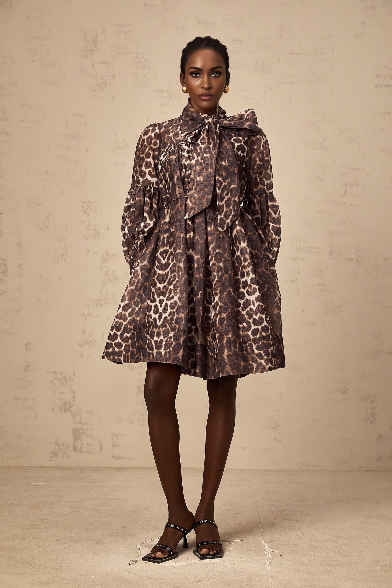 A brown mini dress with leopard print pattern featuring a large bowknot detail and xylene style design