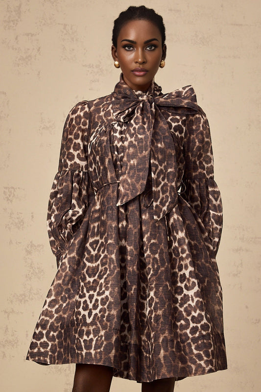 A brown mini dress with leopard print pattern featuring a large bowknot detail in a xylene color