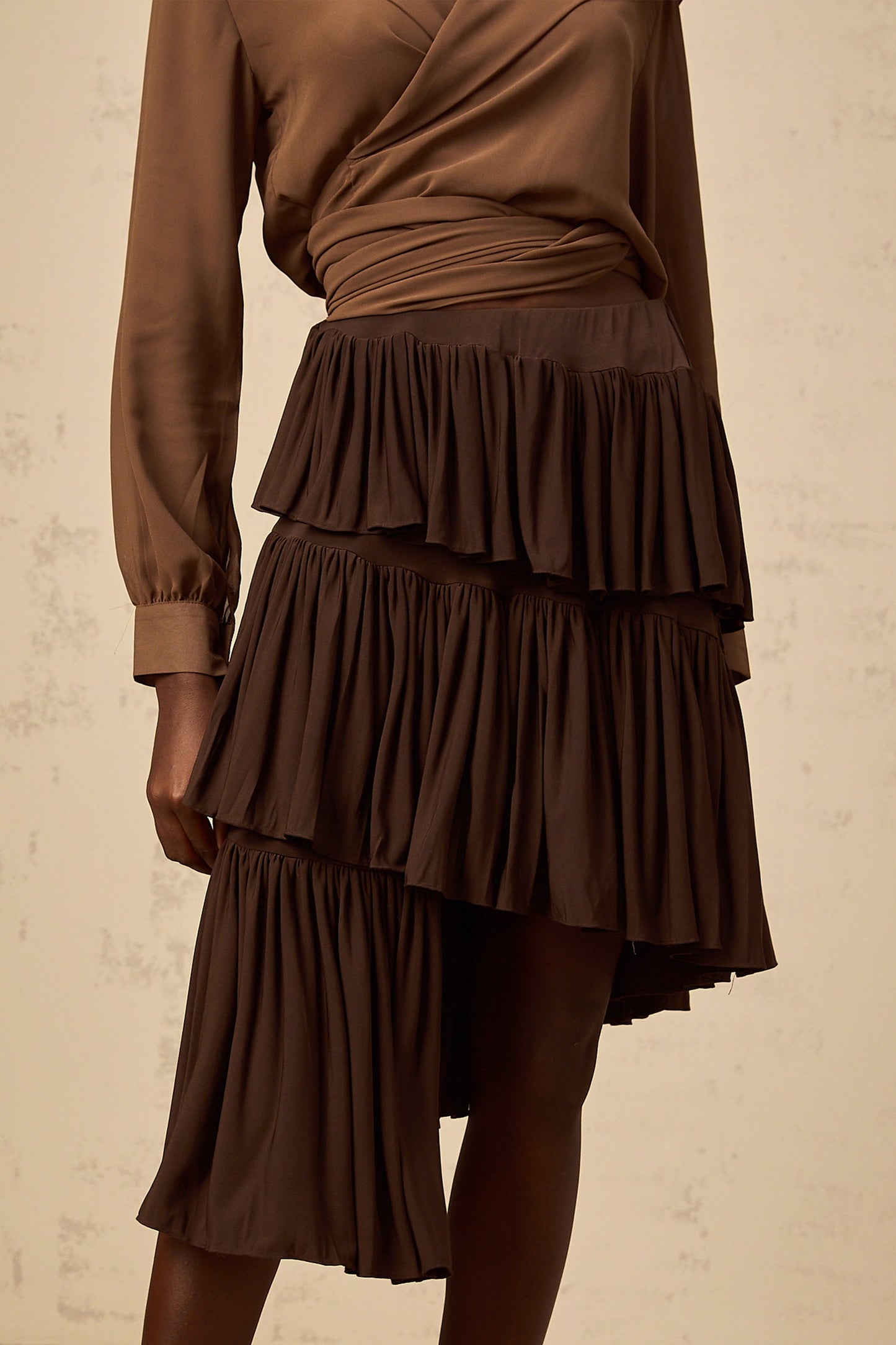 A brown mini skirt with asymmetrical pleated tiers and an uneven hemline named Astrid