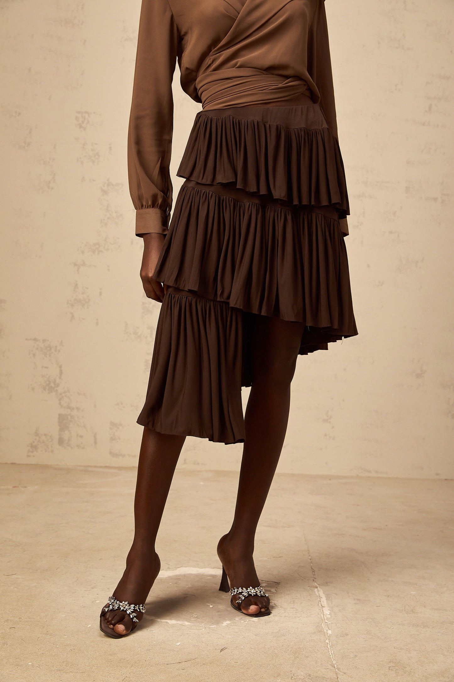 A brown mini skirt with asymmetrical pleated tiers and an uneven hemline named Astrid