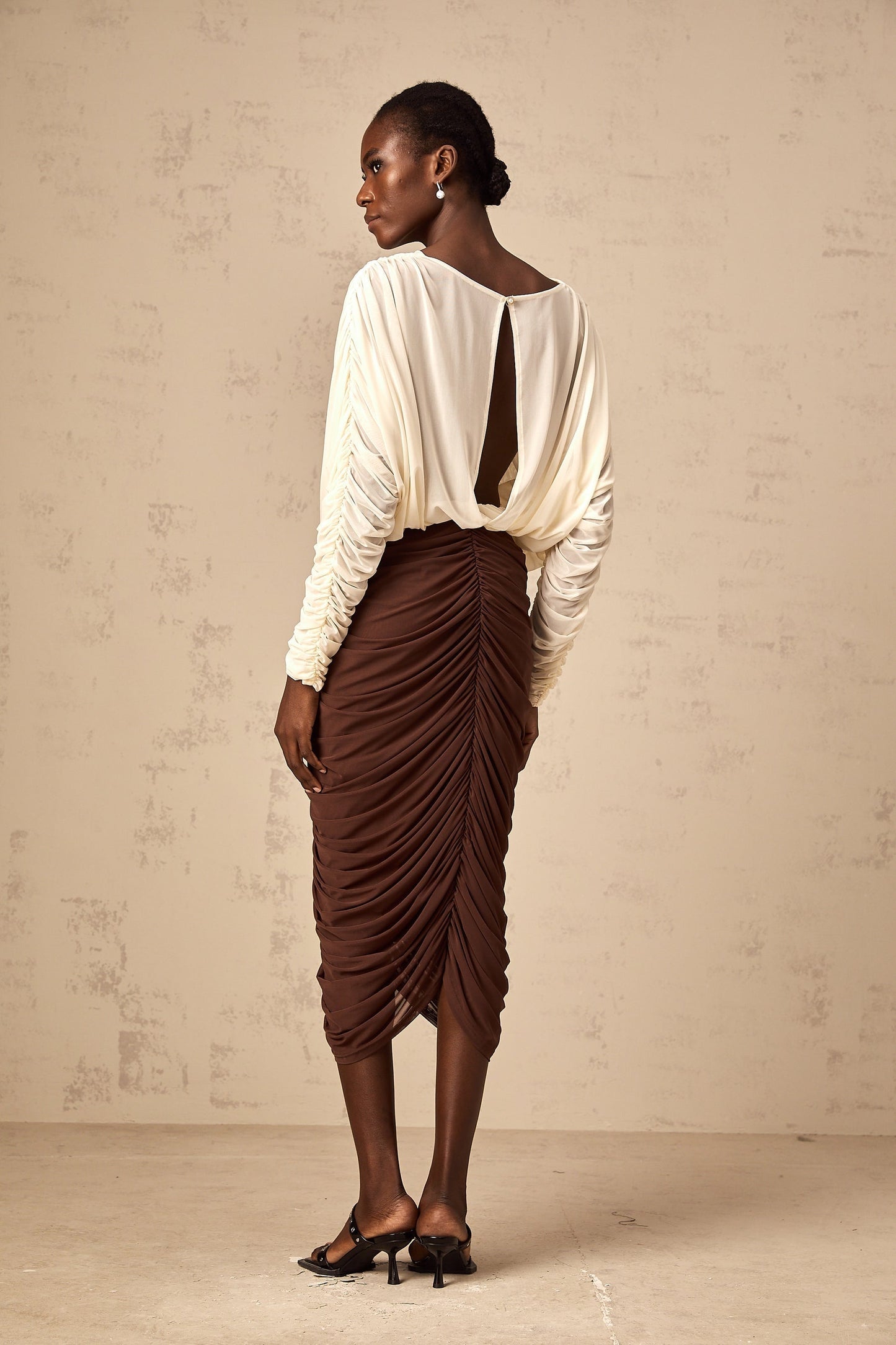 A colorful midi dress with ruched details featuring a prominent flower brooch and color blocking design named Leontine