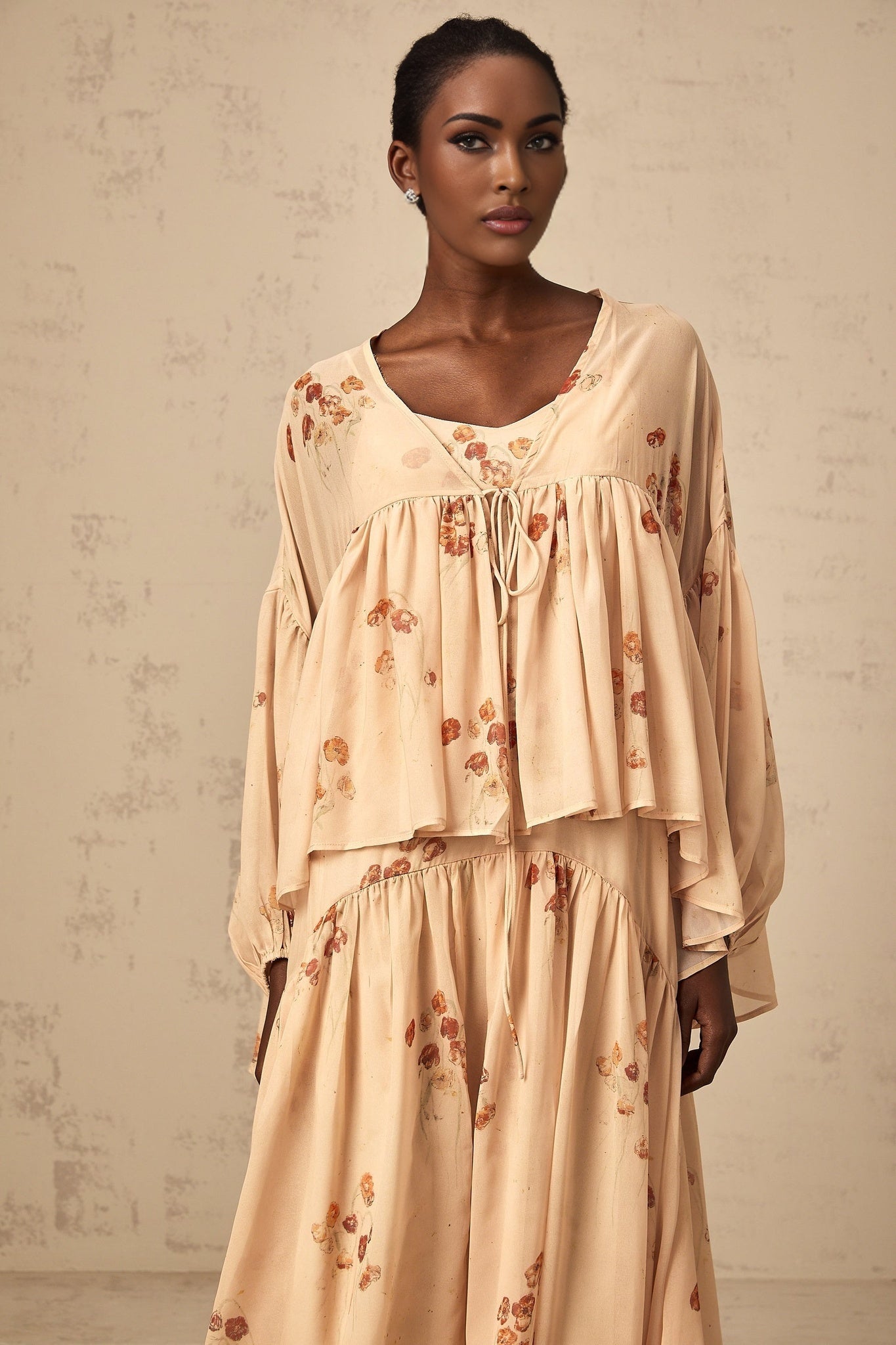 A coralpink matching set featuring a floral print blouse with pleats and a coordinating dress both in a soft feminine style