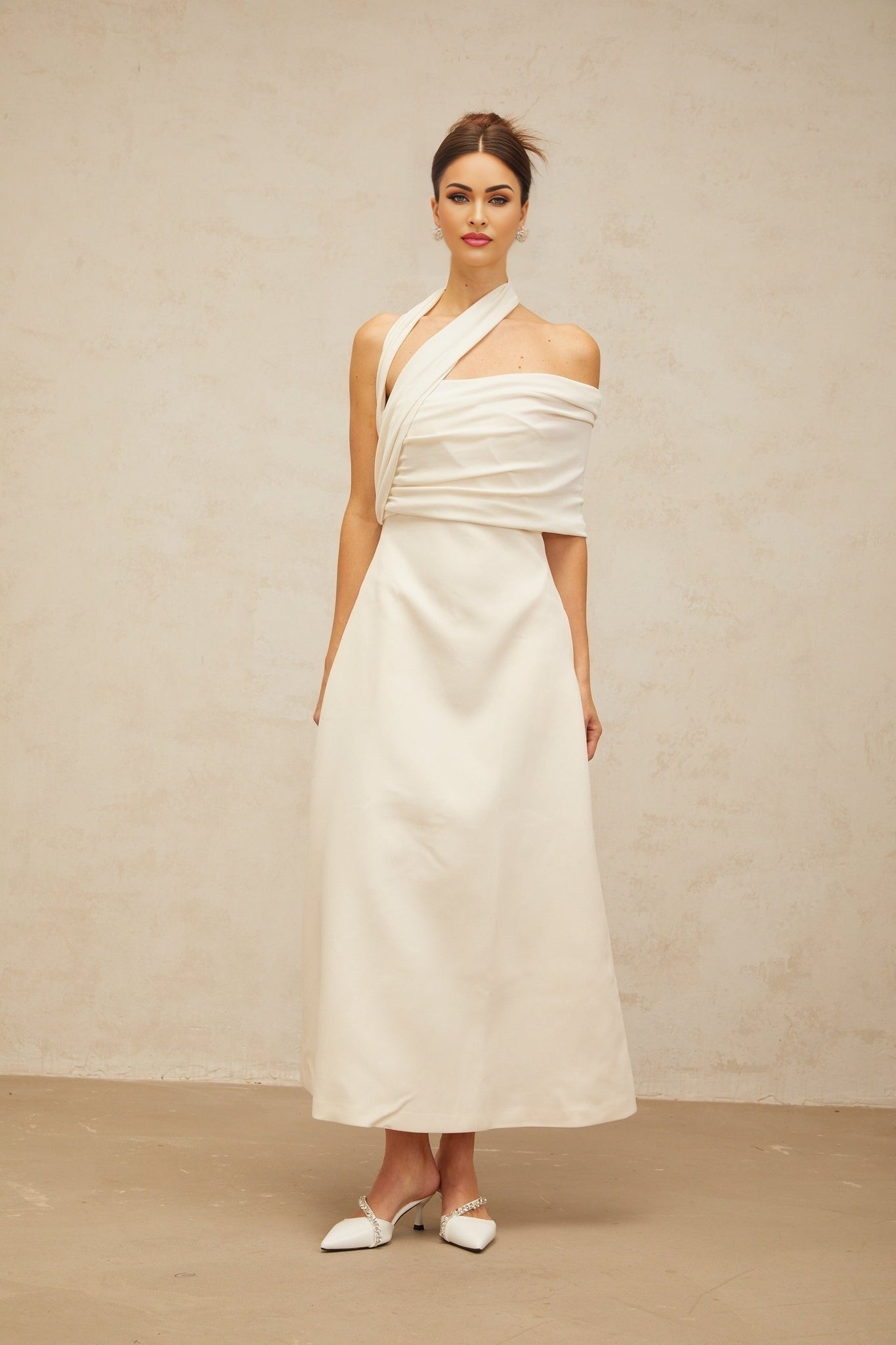A creamwhite asymmetric maxi dress with one shoulder strap and a flowing skirt featuring a side slit