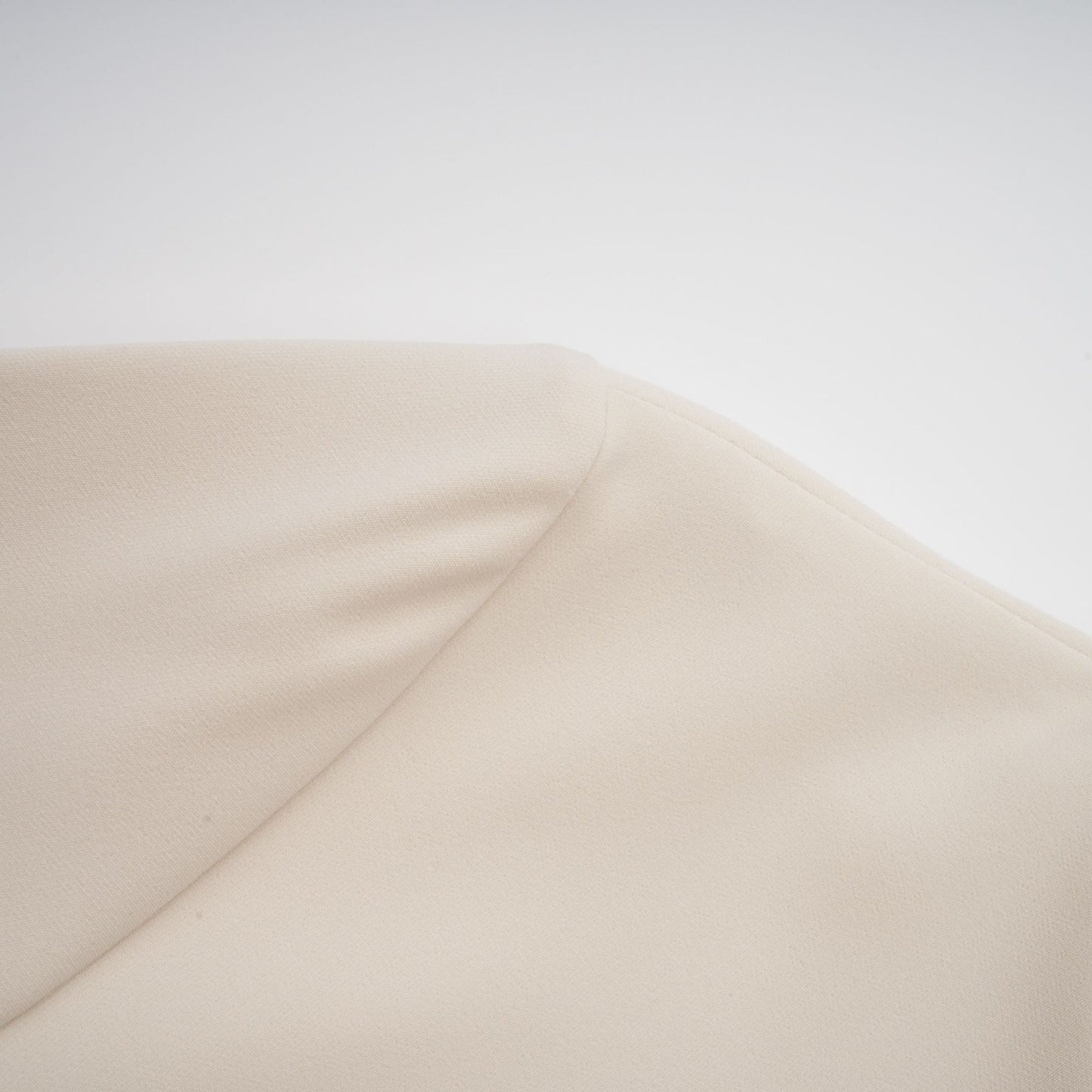 A creamwhite fitted mini dress by Chloé on a plain background showcasing its sleek silhouette and elegant design