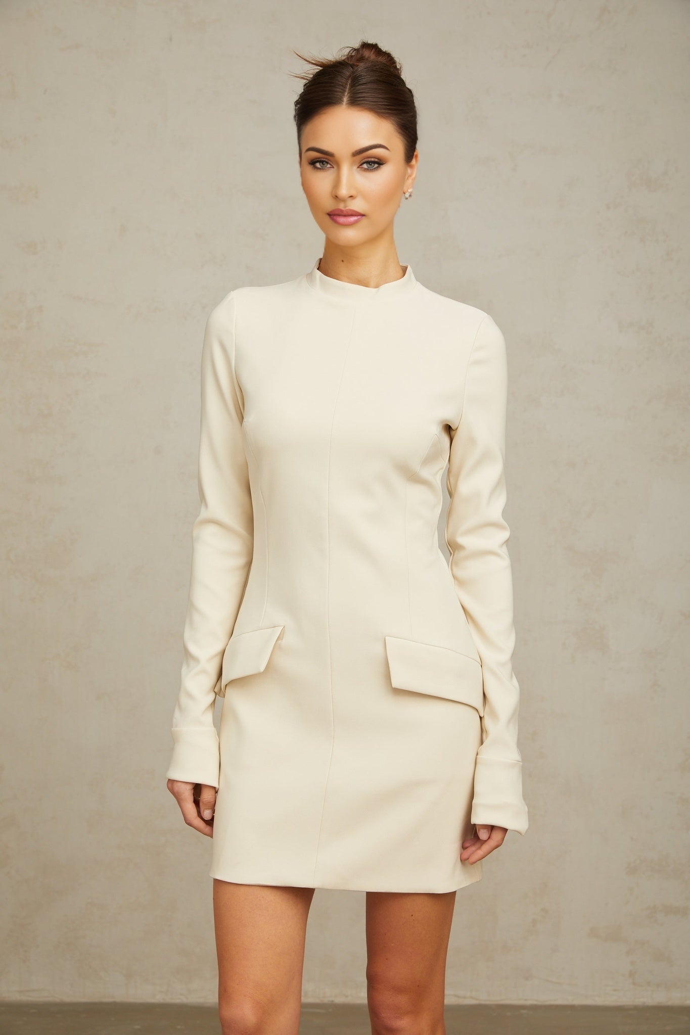 A creamwhite fitted mini dress from Chloé hanging on a display against a plain background showcasing its sleek silhouette and elegant design