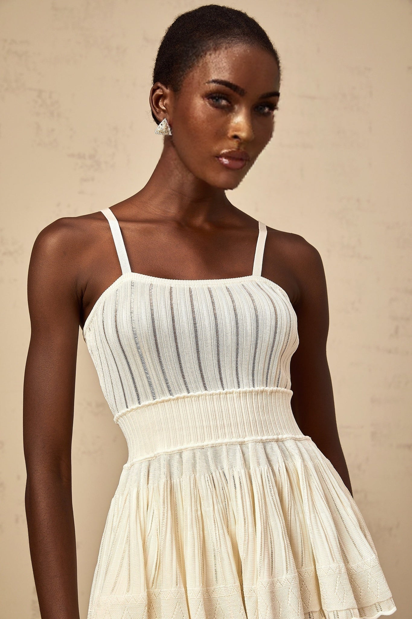 A creamwhite matching set featuring a shirred crochetknit top and culottes The top has a textured pattern and the culottes are loose fitting Both pieces are made from the same knit material